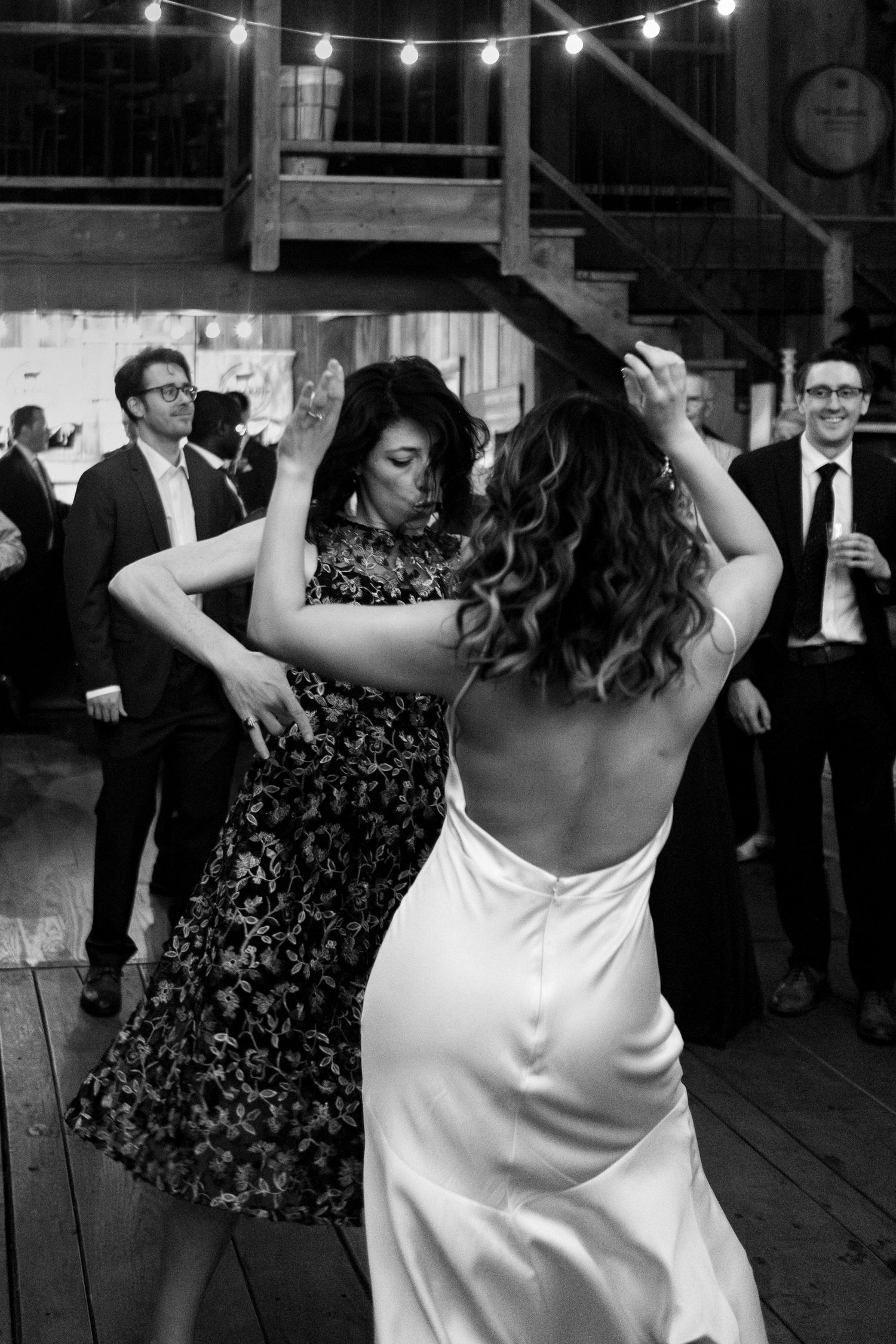 Wedding guest dances with bride in low backed dress on dancefloor of Northern Virginia wedding