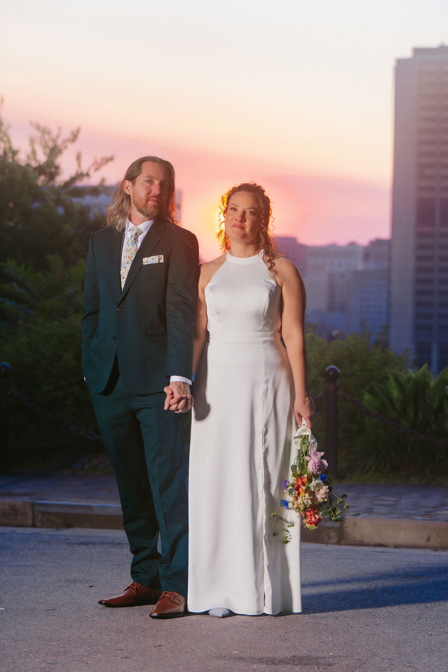 Virginia couple stand before a sunset over the Richmond skyline in their wedding attire