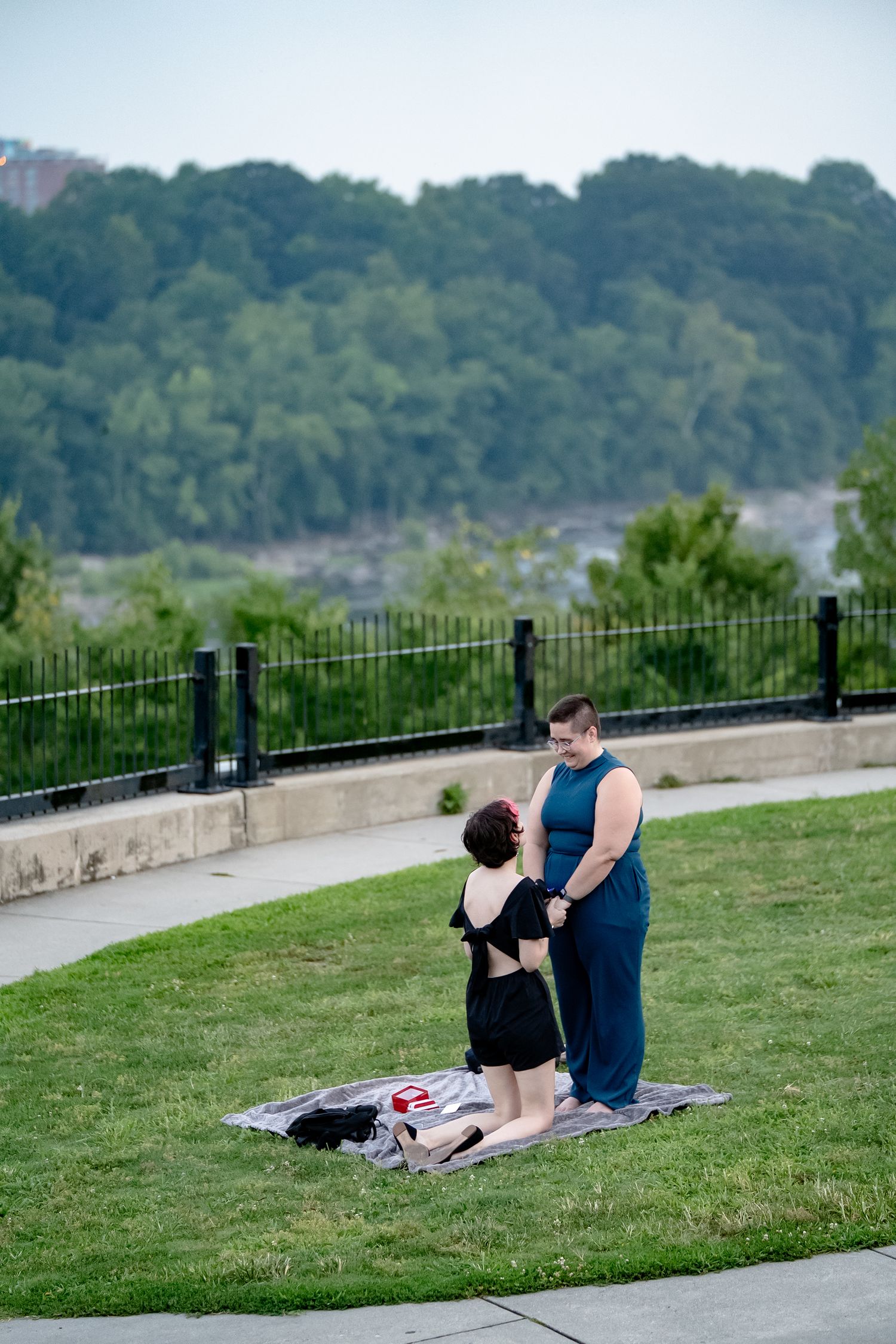 LGBT engagement photo session outdoor picnic far from camera with river and bright summer colors in the background