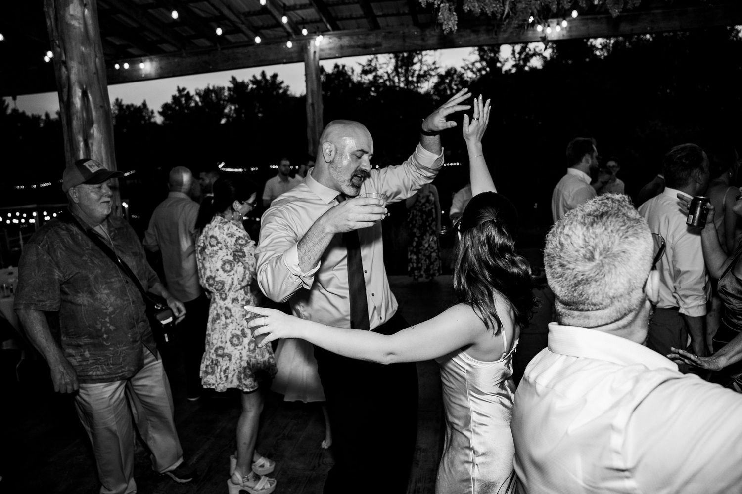 Wedding guest spins on the dancefloor with family under the covered dancefloor in documentary photograph of Avonlea Farms