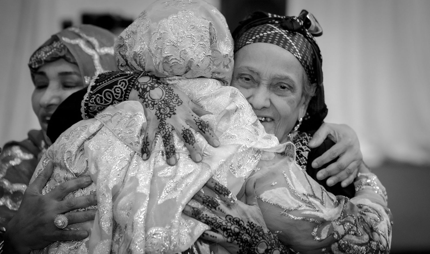 Two women in hijabs sharing a warm embrace at a celebration.