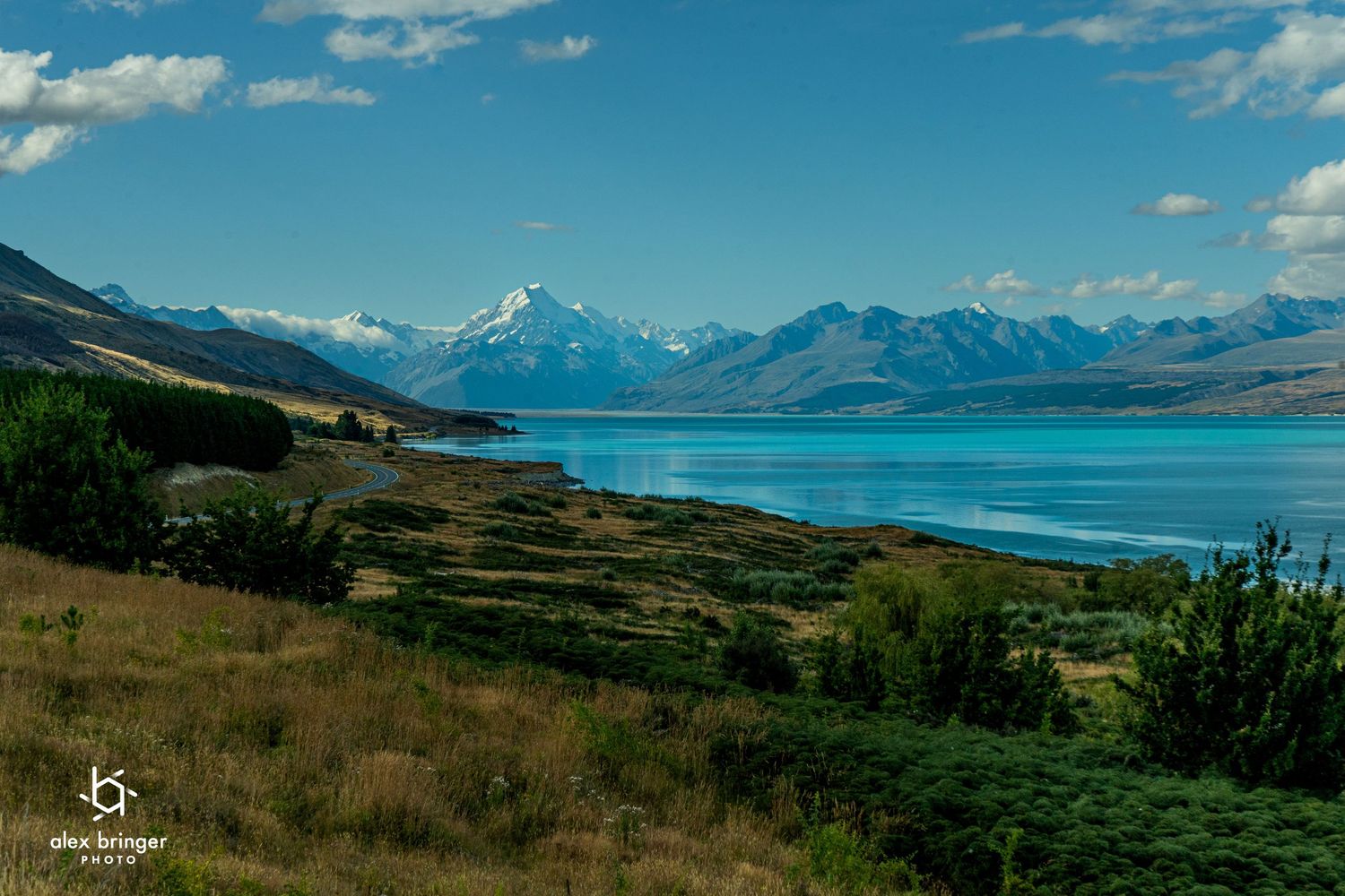 Stunning turquoise Lake Pukaki with snow-capped Mount Cook in the background under a blue sky in New Zealand.
