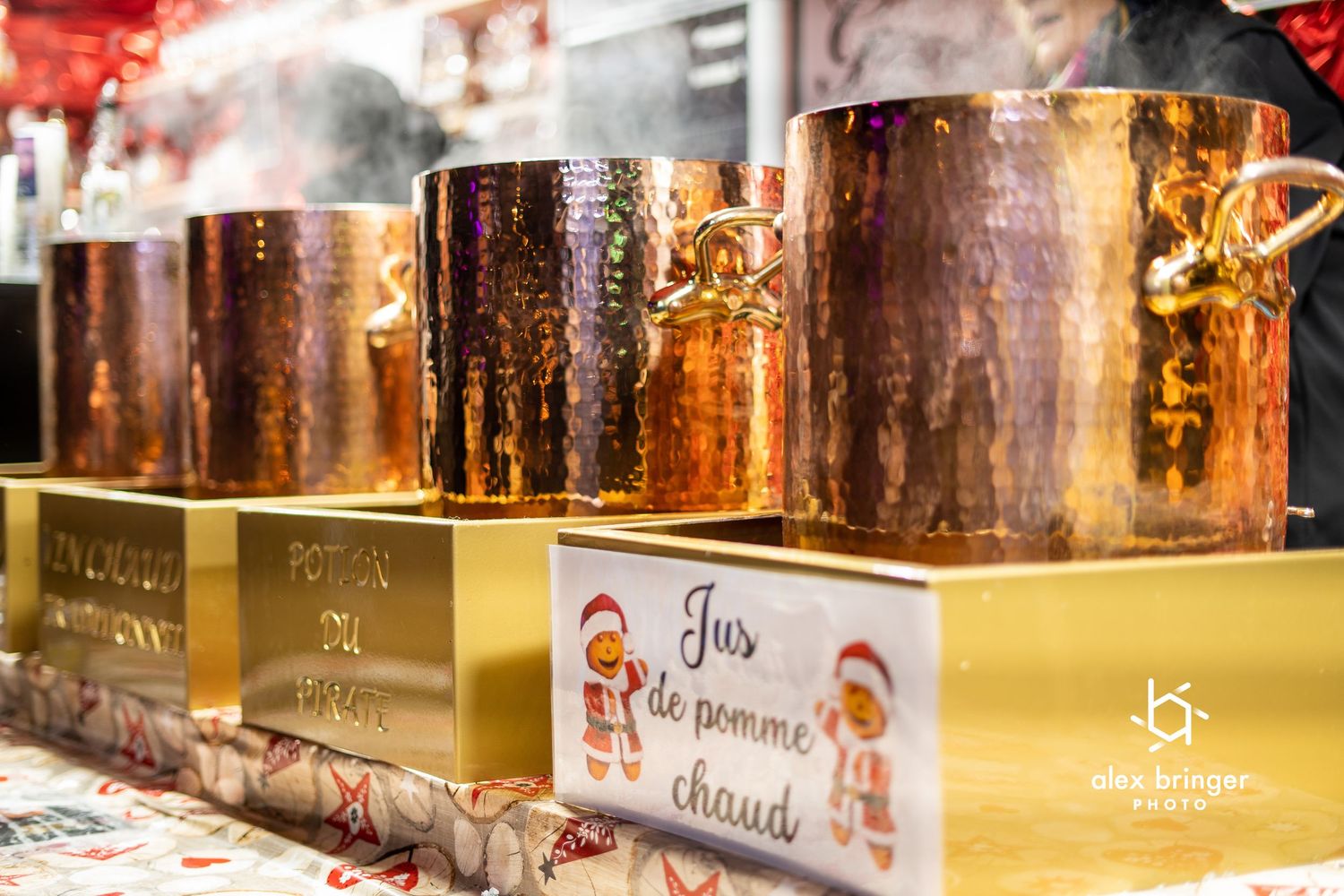 Shiny copper pots displayed at a festive Christmas market hot apple juice stand.