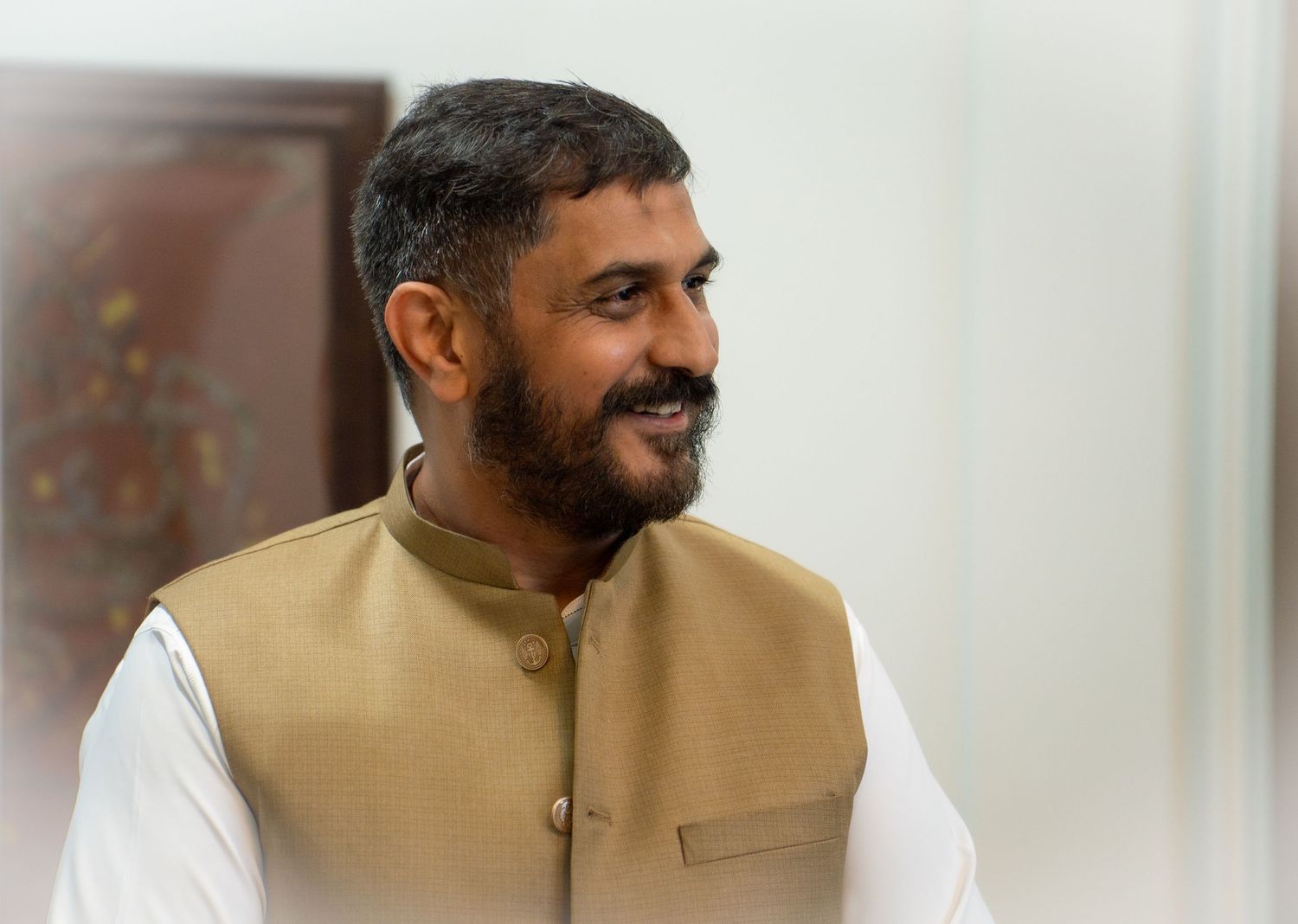 Smiling bearded man in traditional Indian kurta and Nehru jacket.