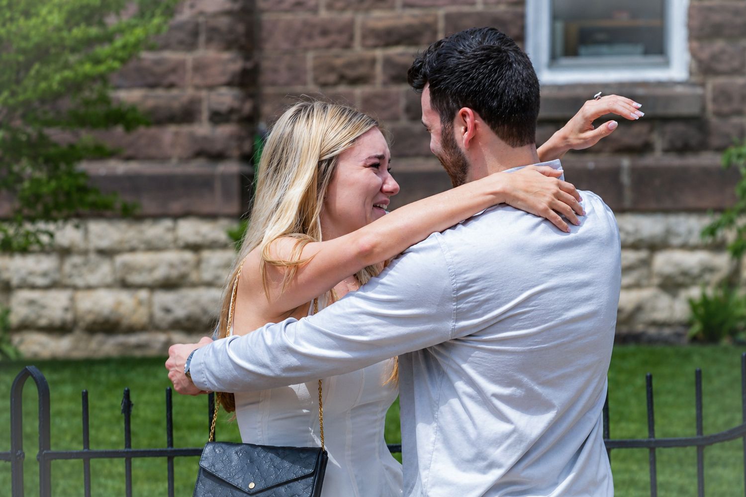 Happy couple embracing and smiling at each other outdoors in a park setting.