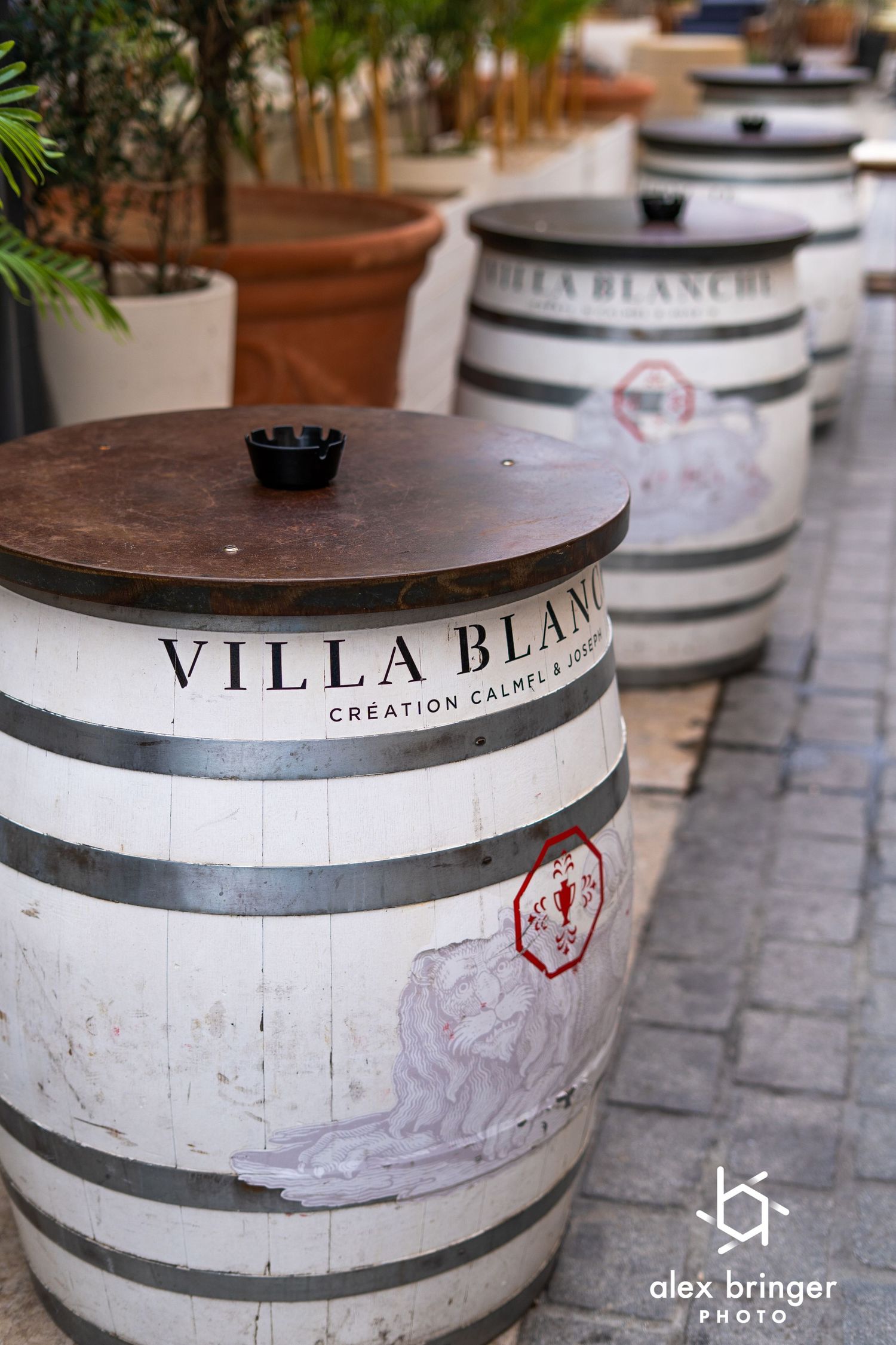 White wooden wine barrels labeled Villa Blanche displayed on an outdoor restaurant patio.