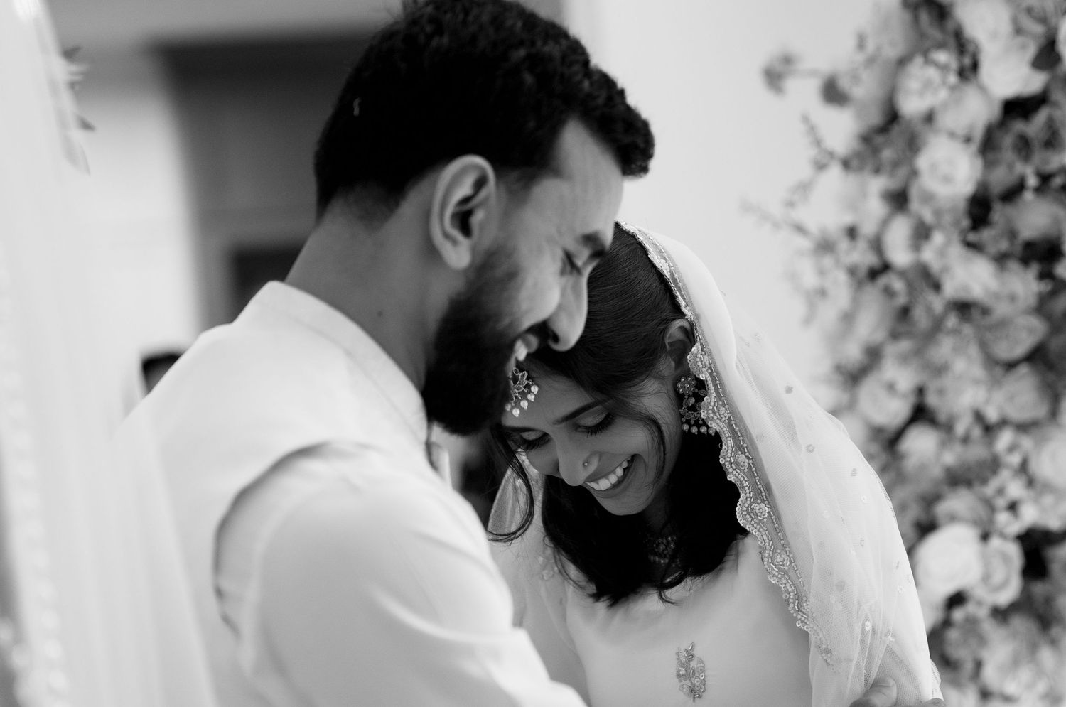 Black and white photo of a bride and groom sharing an intimate moment.