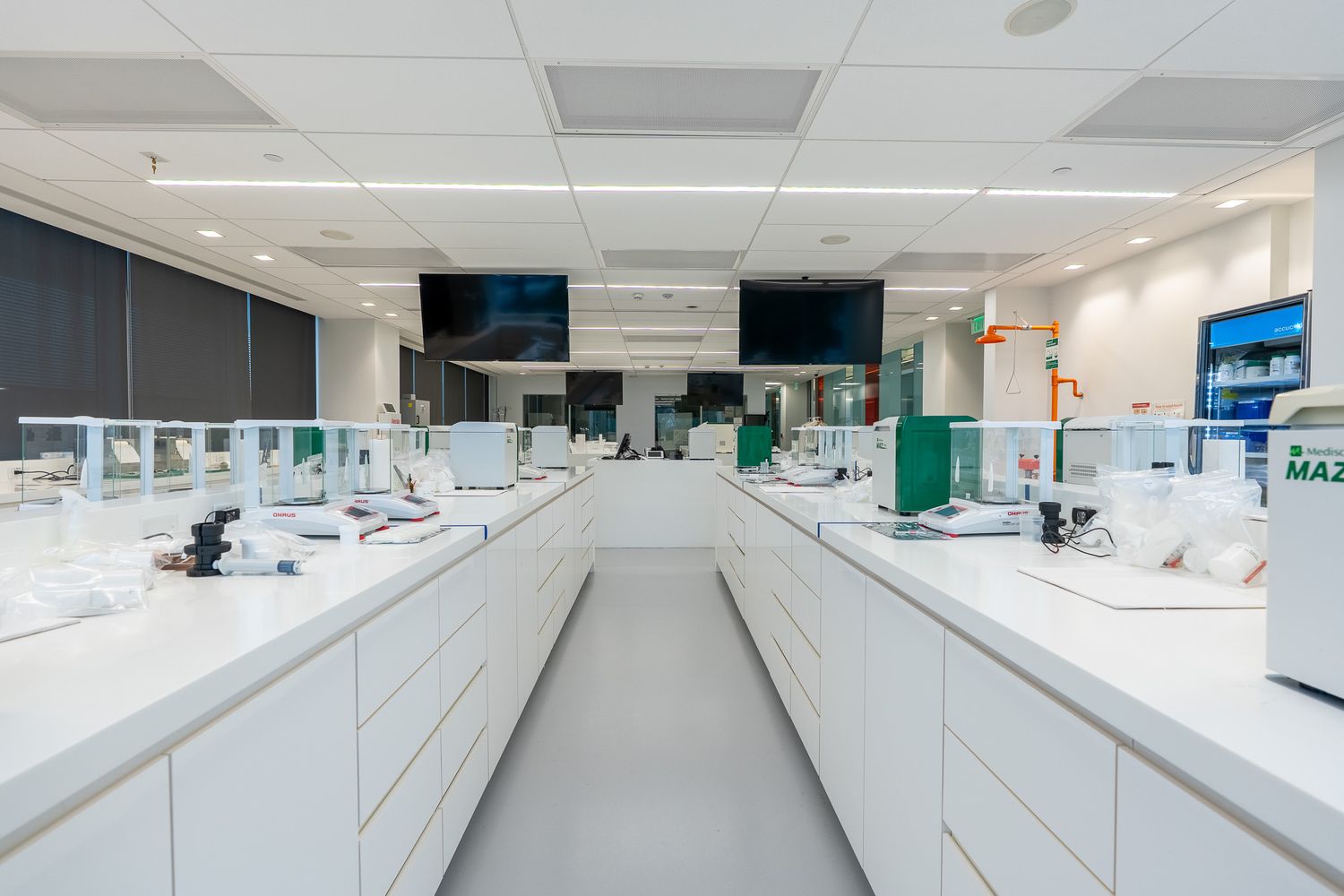 Modern white laboratory with long benches, scientific equipment, and bright overhead lighting in a clean research facility.