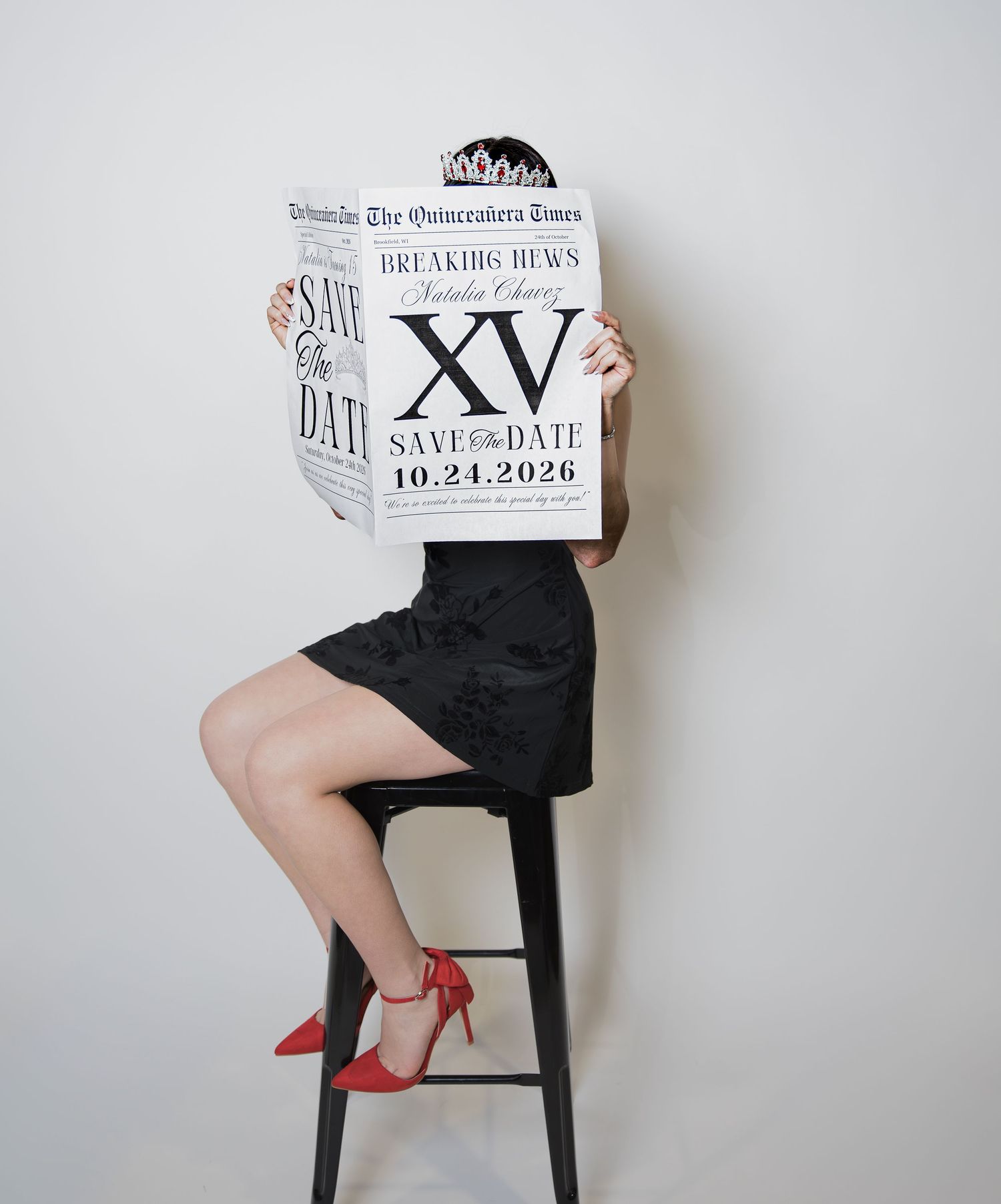 Girl in black dress and red heels holds Quinceanera Times newspaper save the date for XV party on 10.24.2026.