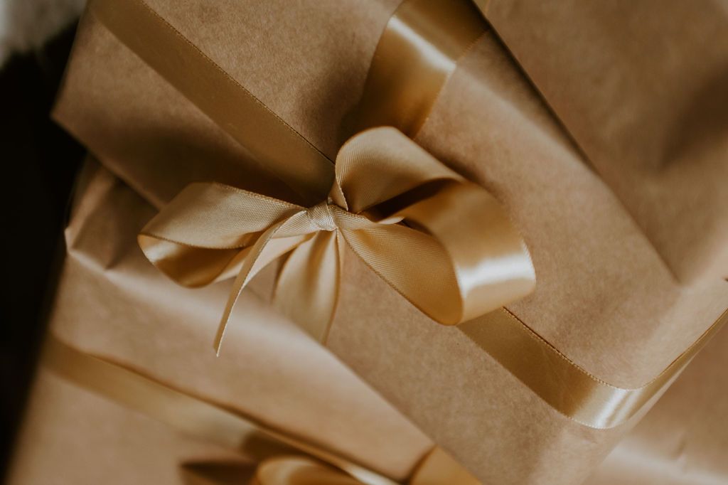 Elegant gift boxes wrapped in kraft paper with luxurious gold satin ribbon bows, perfect for special occasions.
