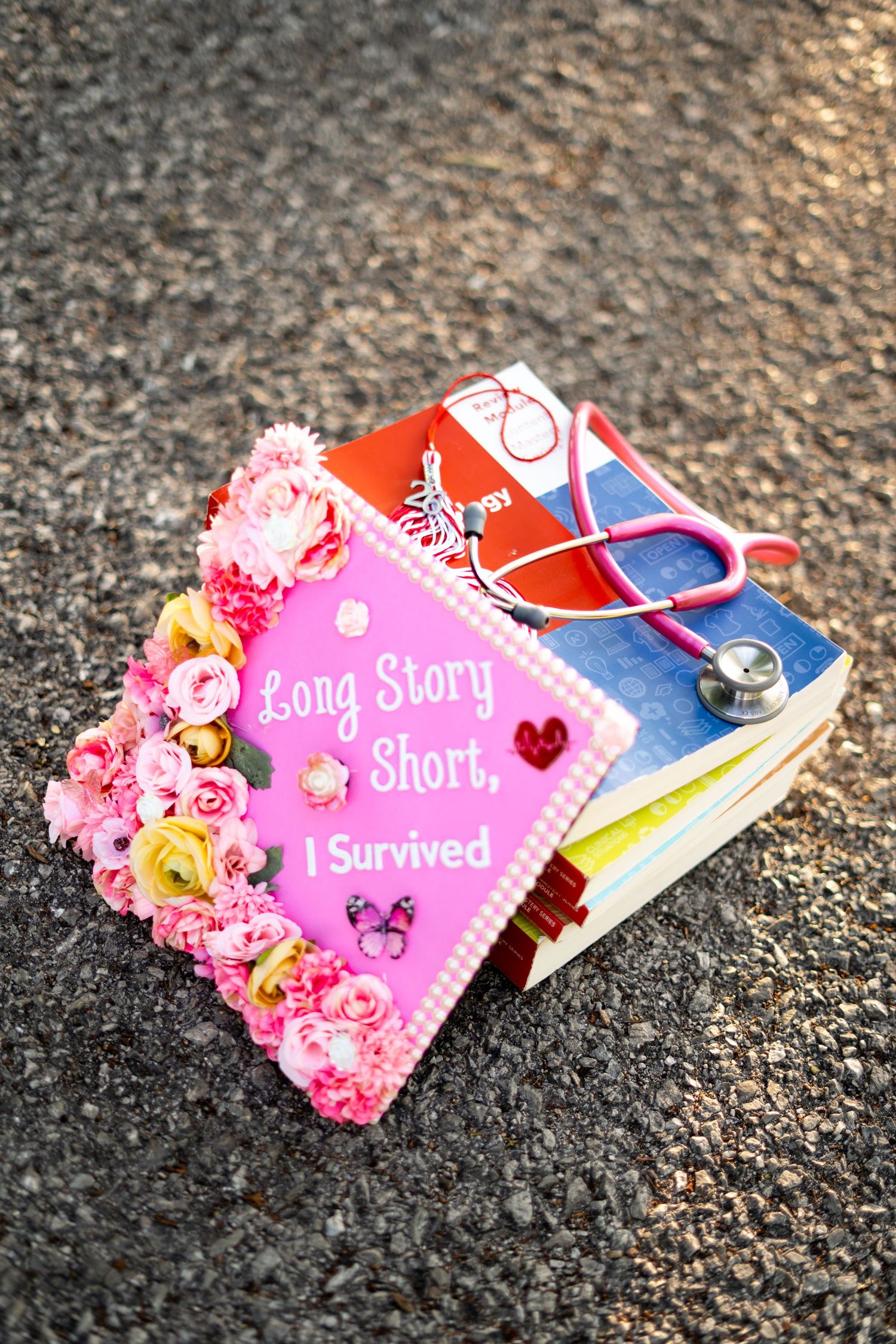 Decorated pink nursing graduation cap reads Long Story Short I Survived with stethoscope.