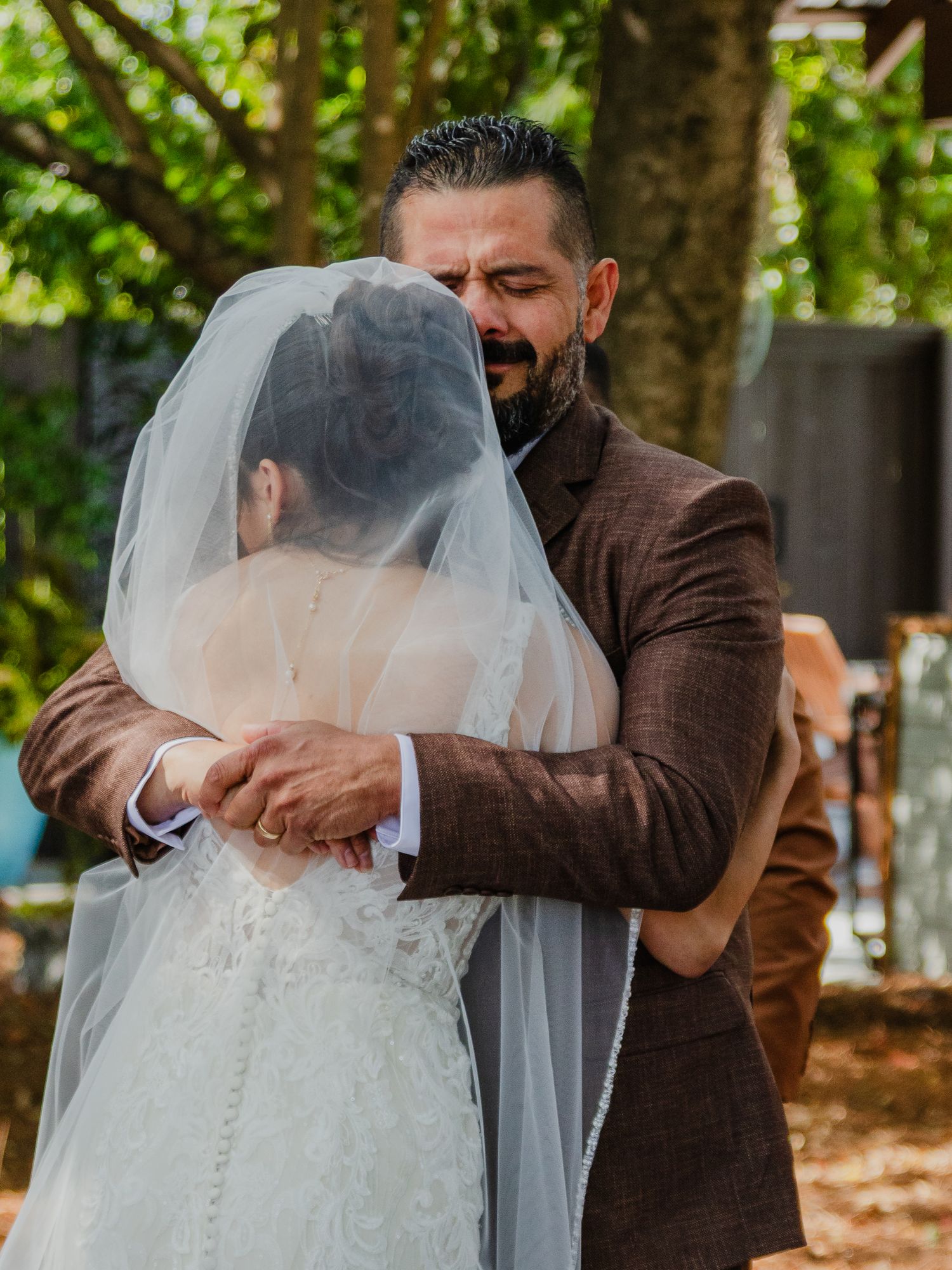 A couple shares an emotional first look moment at their outdoor wedding surrounded by trees and autumn leaves.