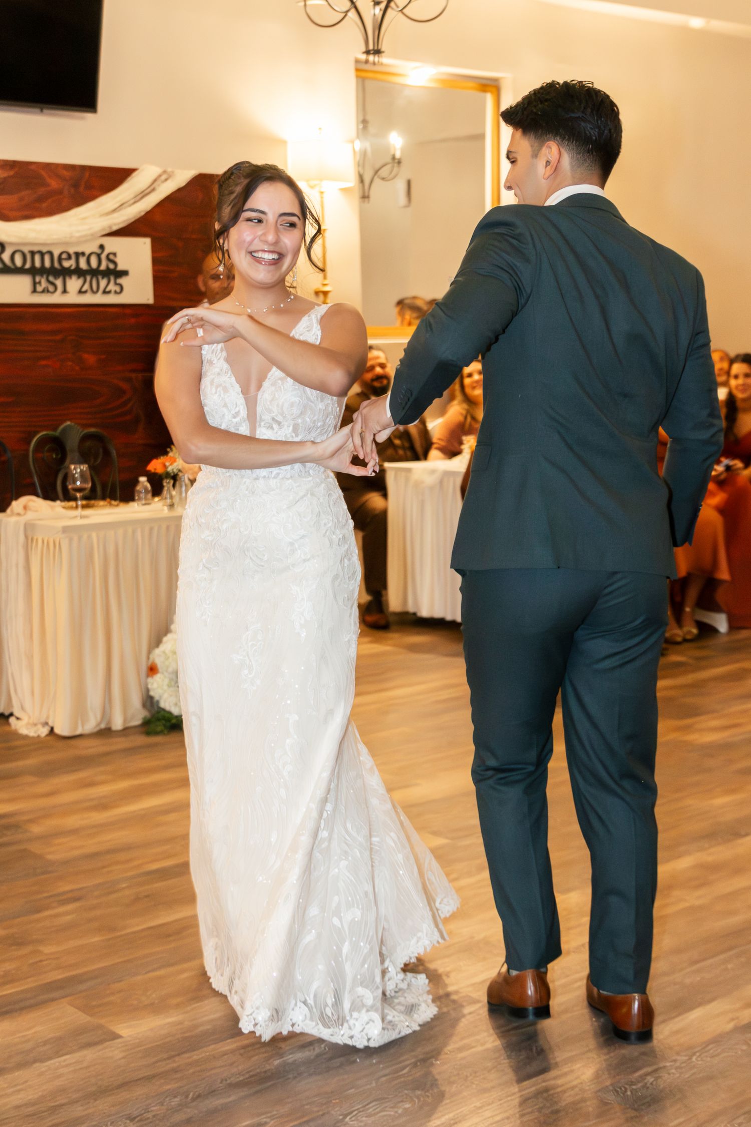 A couple shares their first dance at a wedding reception on a hardwood floor with white drapes in the background. Lexington Wedding
