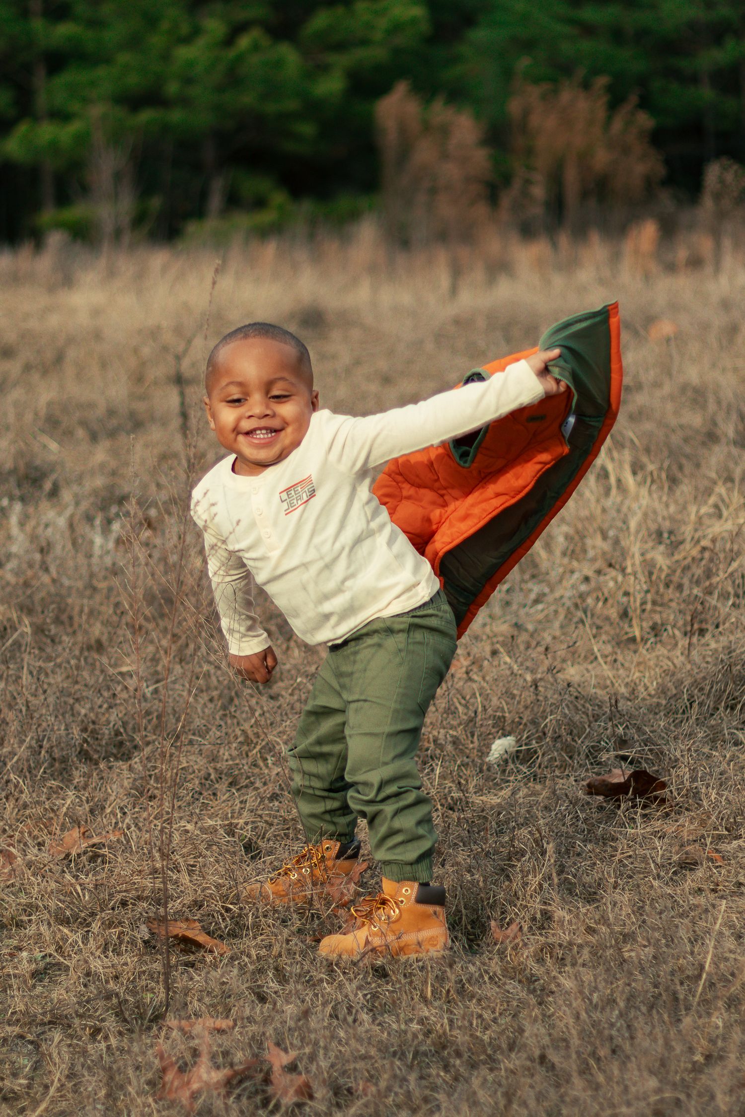 A sequence of photos showing a small child in a cream sweater and green pants falling over in a field.