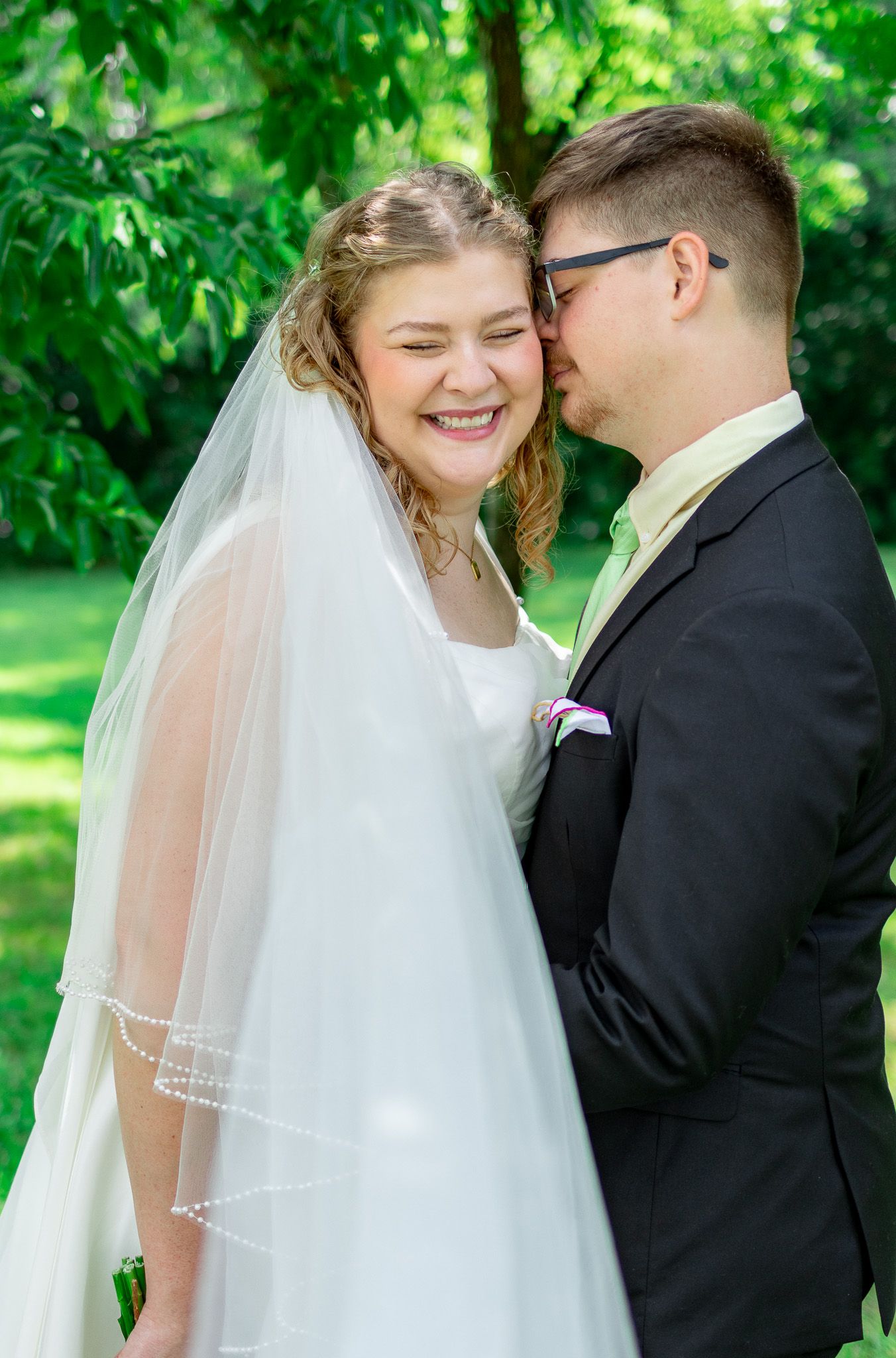 Bride and groom sharing a joyful moment outdoors on their wedding day.