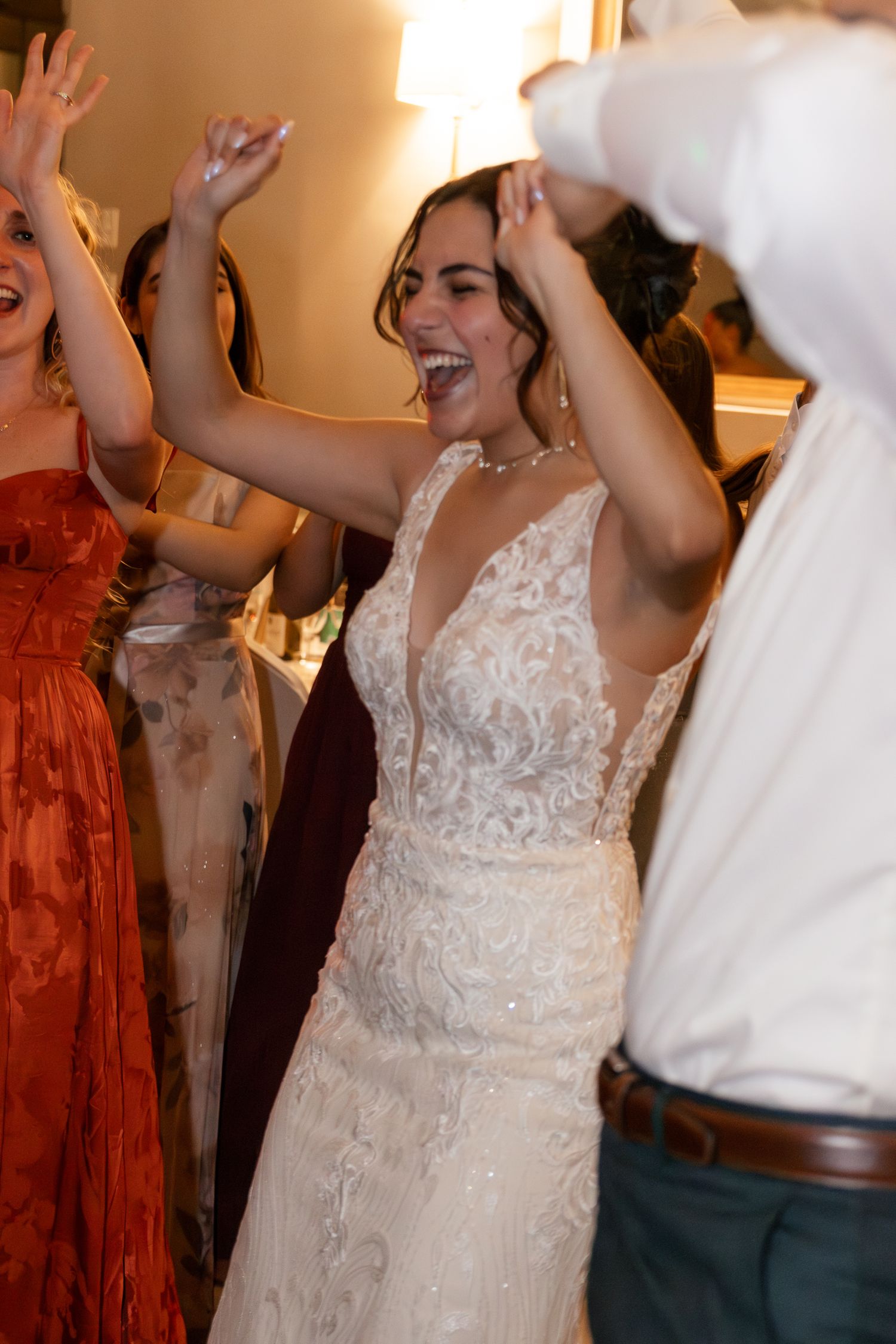 A bride in a white lace wedding dress dances joyfully at a reception celebration. Lexington Wedding Photographer
