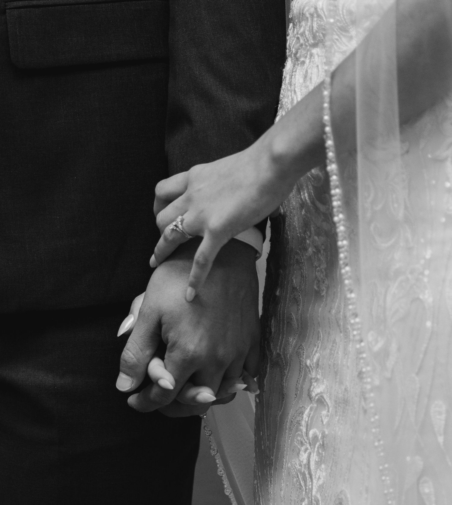 Close-up black and white shot of a couple holding hands, with the bride wearing a delicate lace wedding dress. South Carolina Wedding
