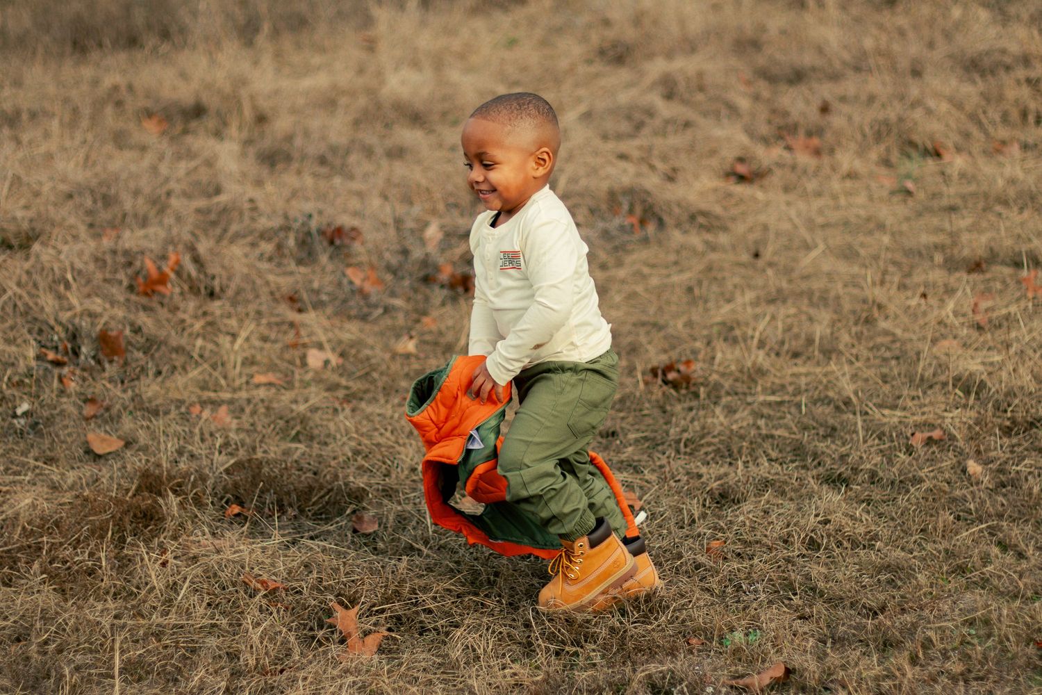 A series of action shots showing a child in orange pants playing and running in a dry grassy field.