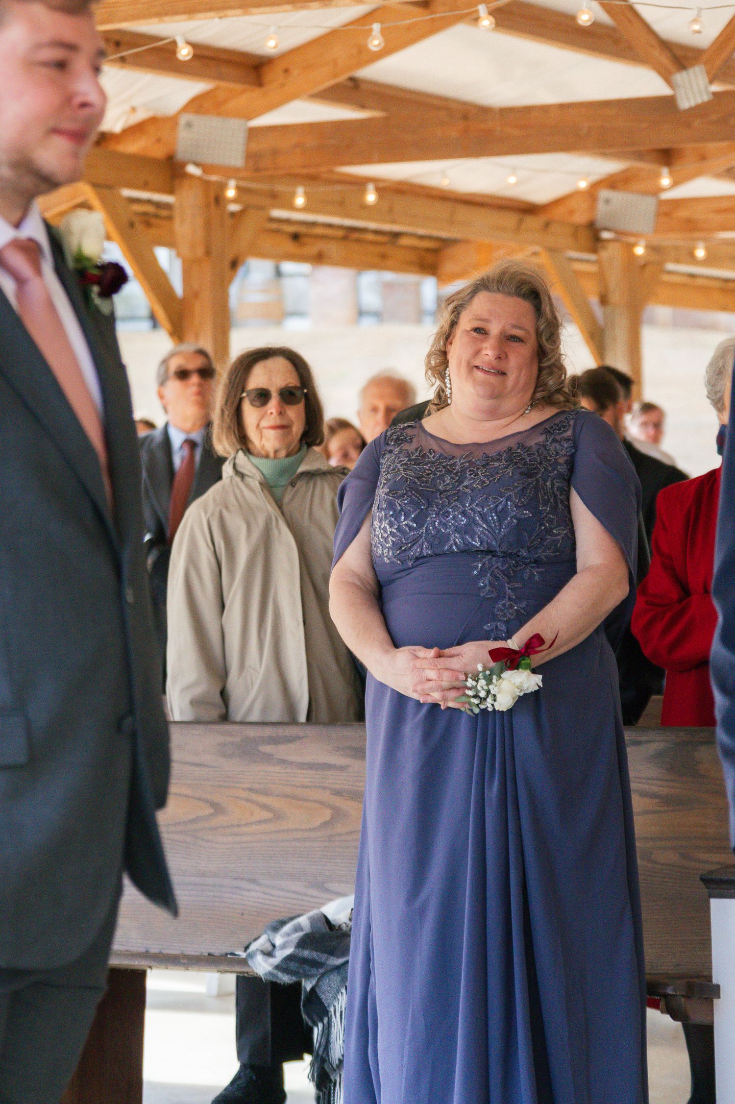 A person wearing a navy blue formal dress stands in a rustic wooden venue during a special event.