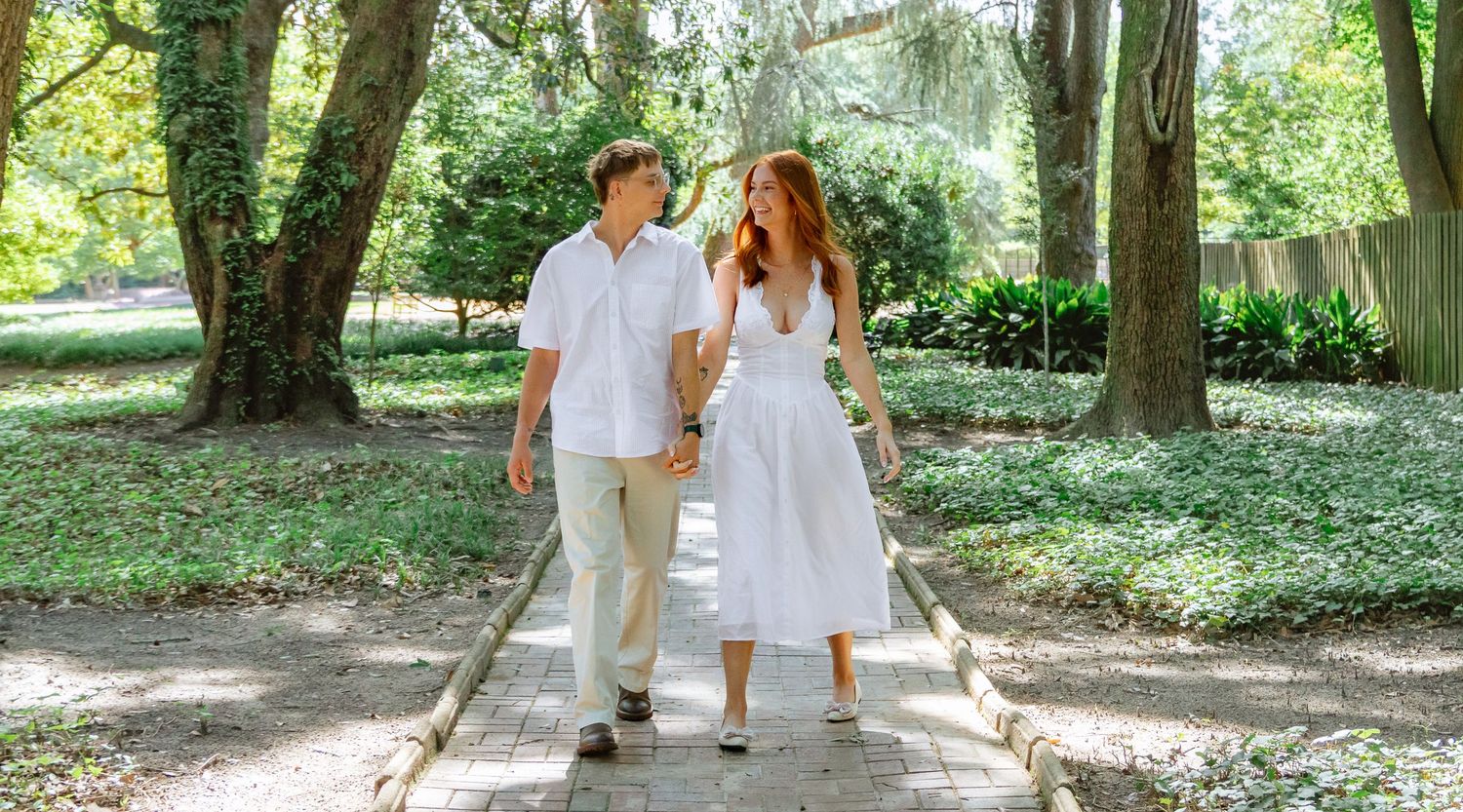 Engaged couple walking hand in hand along a garden path during an Aiken, South Carolina engagement session.