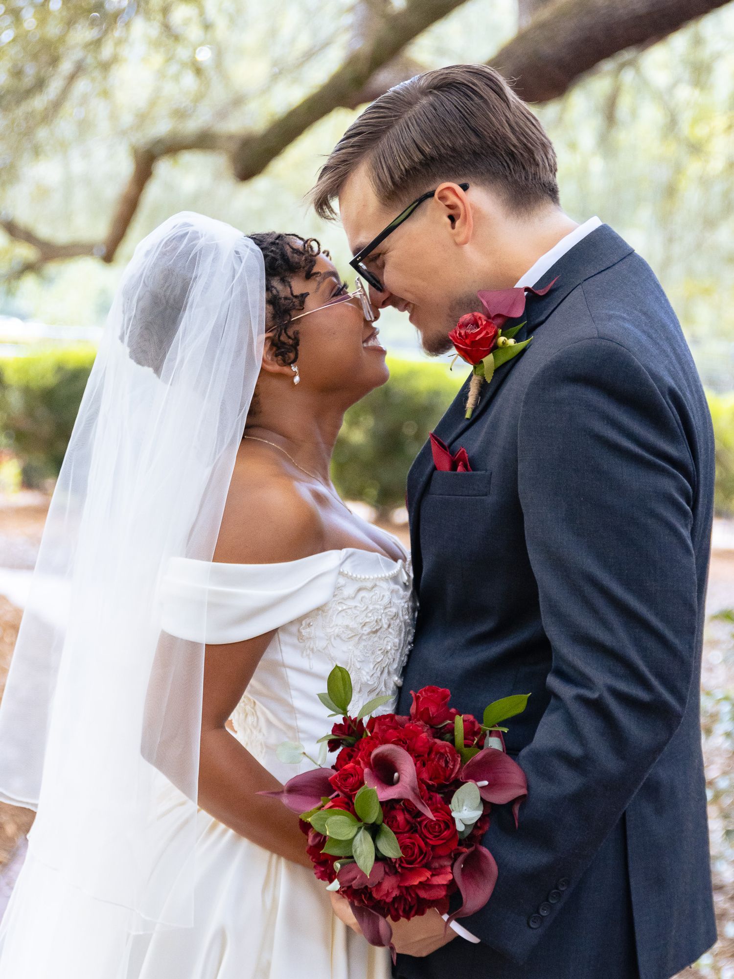 Bride and groom sharing a romantic moment on their South Carolina wedding day, with the bride holding a red bouquet.