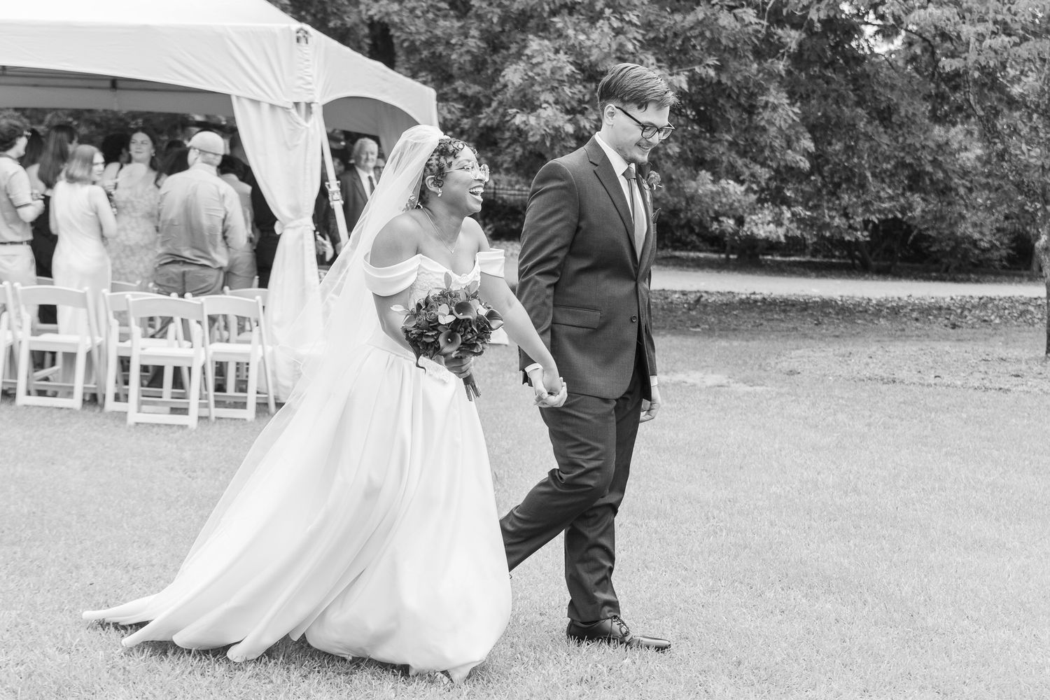 Black and white wedding photograph of a bride and groom walking together outdoors at their Aiken South Carolina Wedding Venue.