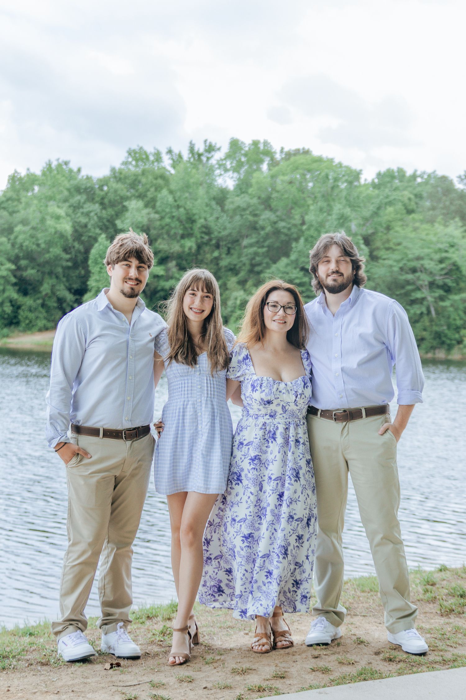 Two young men and two young women pose together smiling in front of a beautiful lakeside backdrop.