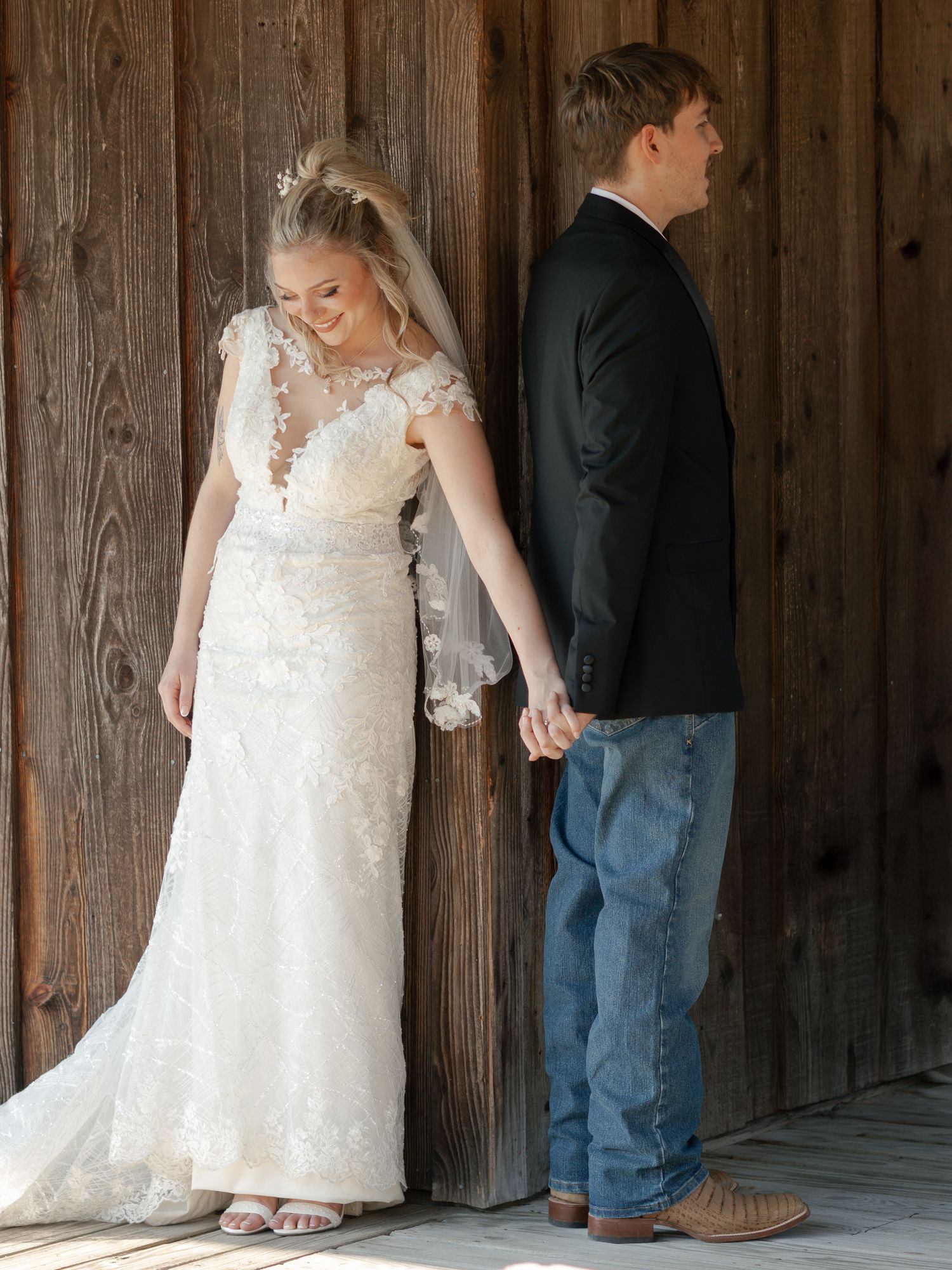 A couple shares a private first look moment against a rustic wooden wall before their wedding ceremony.