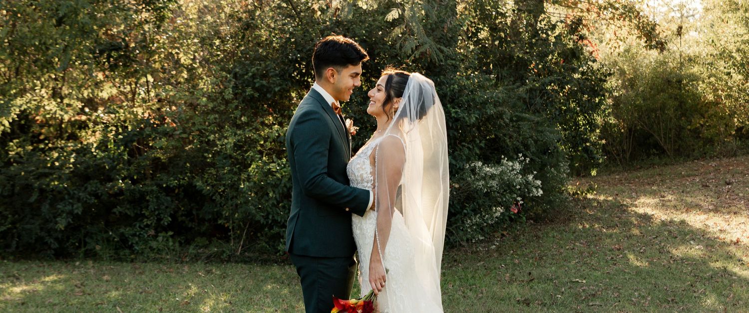A couple embraces in a romantic outdoor garden setting with sunlight filtering through the trees. South Carolina Wedding Photographer