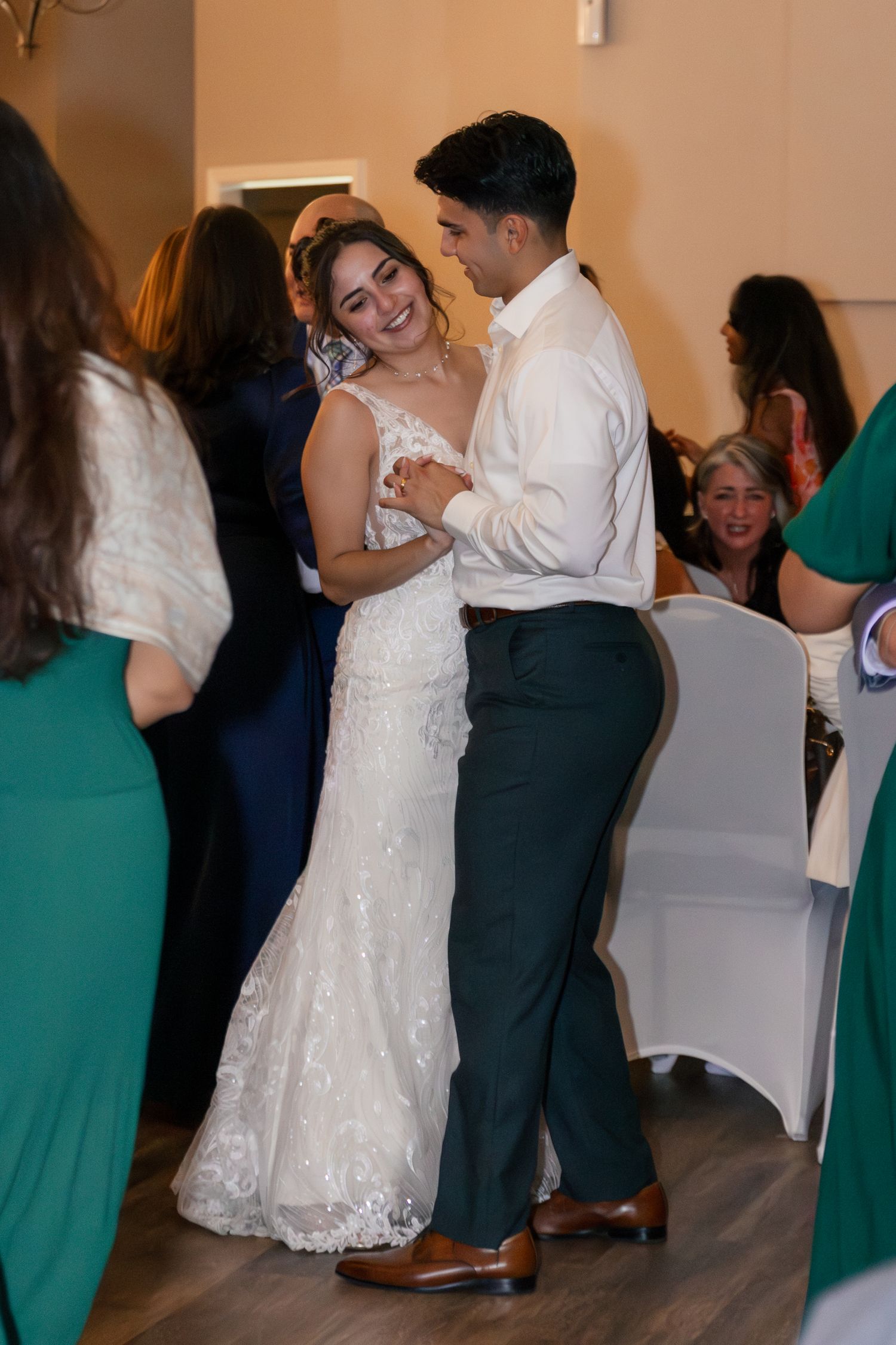 A couple shares their first dance at a wedding reception, surrounded by guests in emerald green dresses. Lexington Wedding Photographer