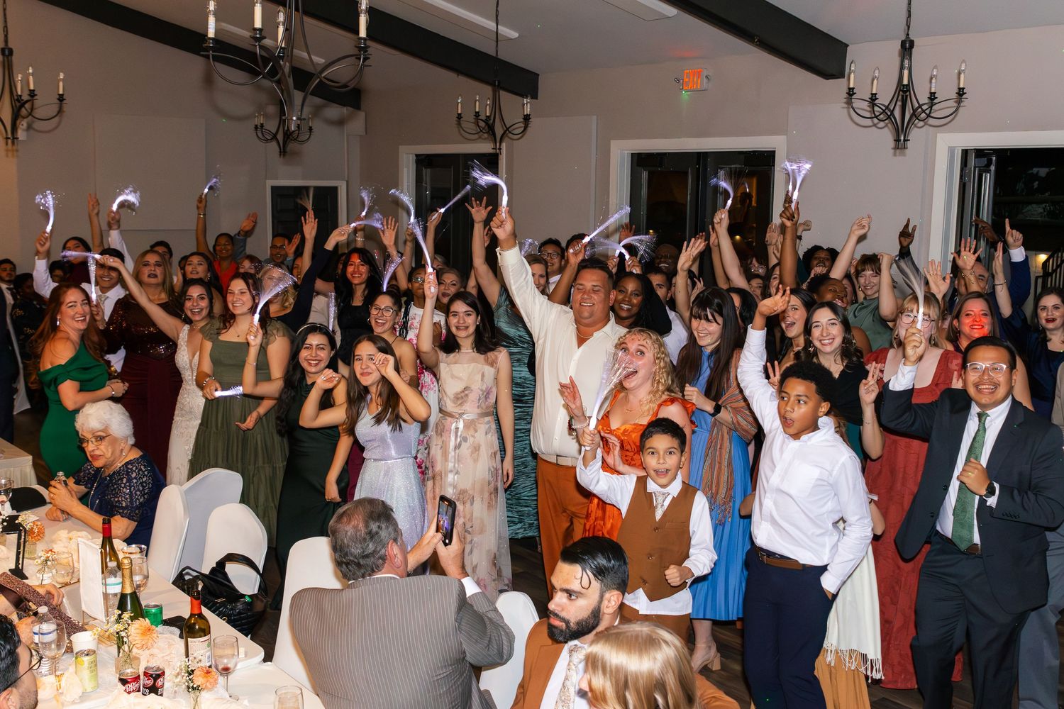 Wedding reception guests raise their hands and dance together on a crowded dance floor during a celebration. Aiken Wedding Photographer