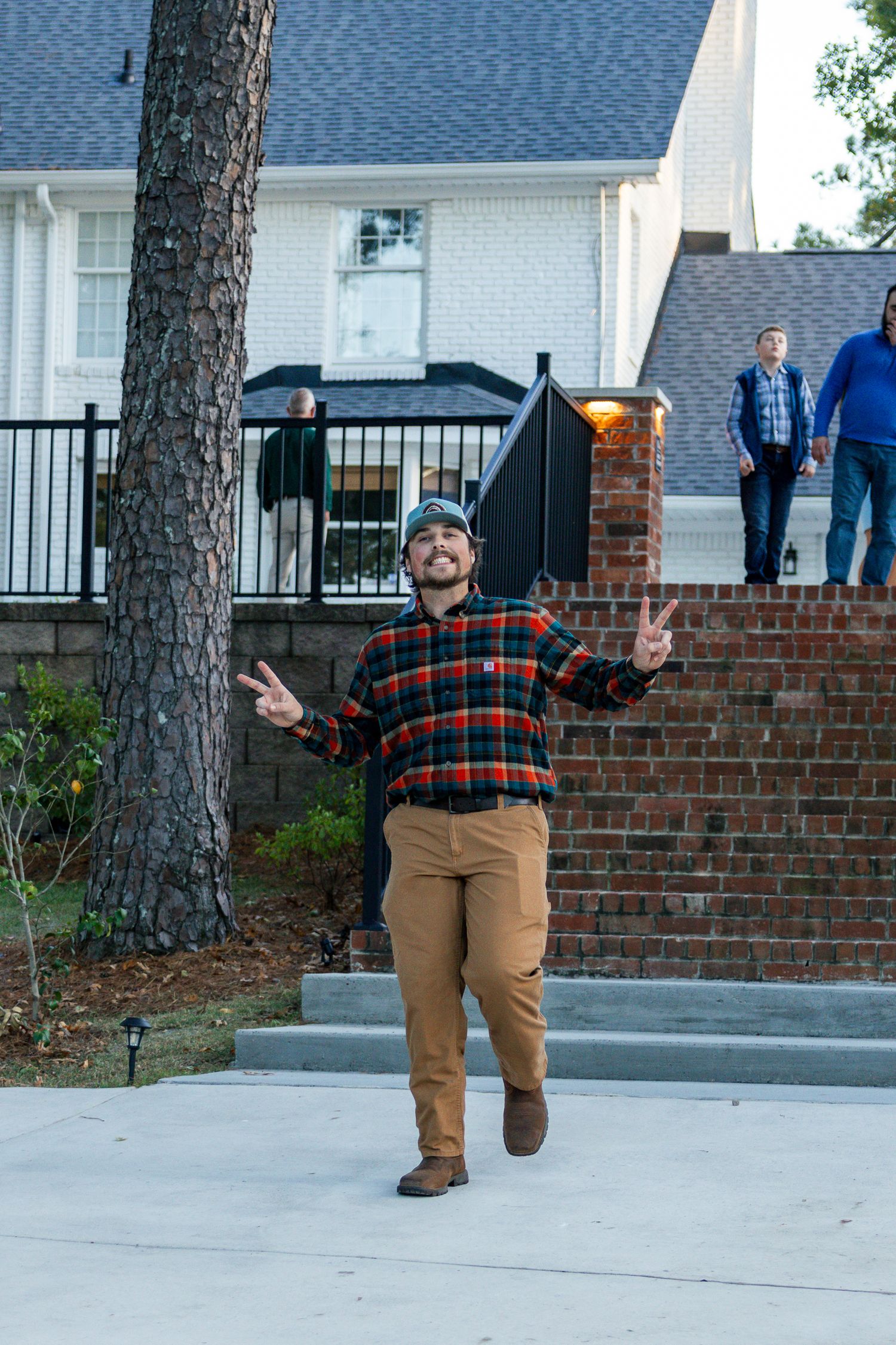 A series of photos showing someone in a plaid shirt and khakis making peace signs while posing on a driveway.