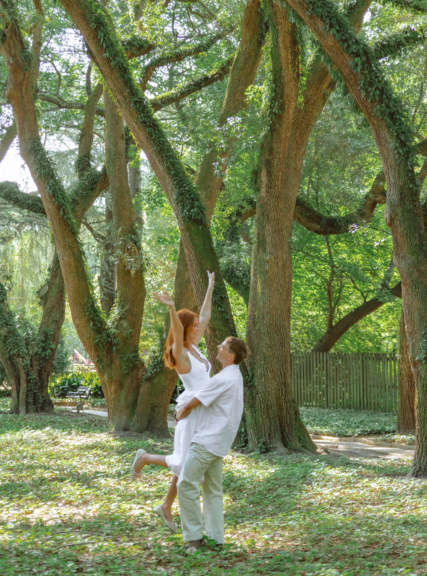 Engaged couple dancing together beneath moss-covered trees during an Aiken, South Carolina engagement session.
