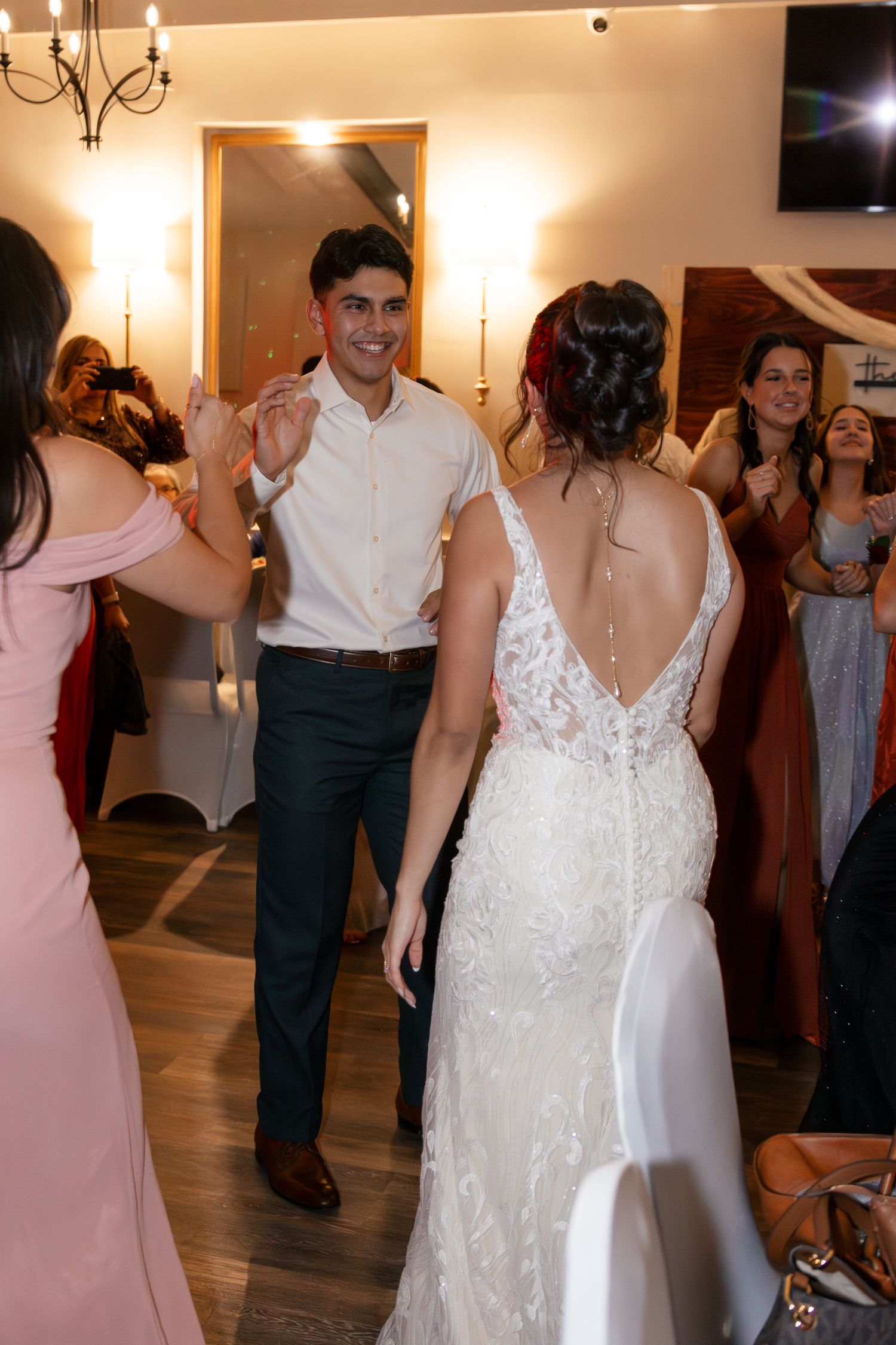 Wedding guests dancing and celebrating at an indoor reception venue with warm lighting and hardwood floors. Lexington Wedding Photographer