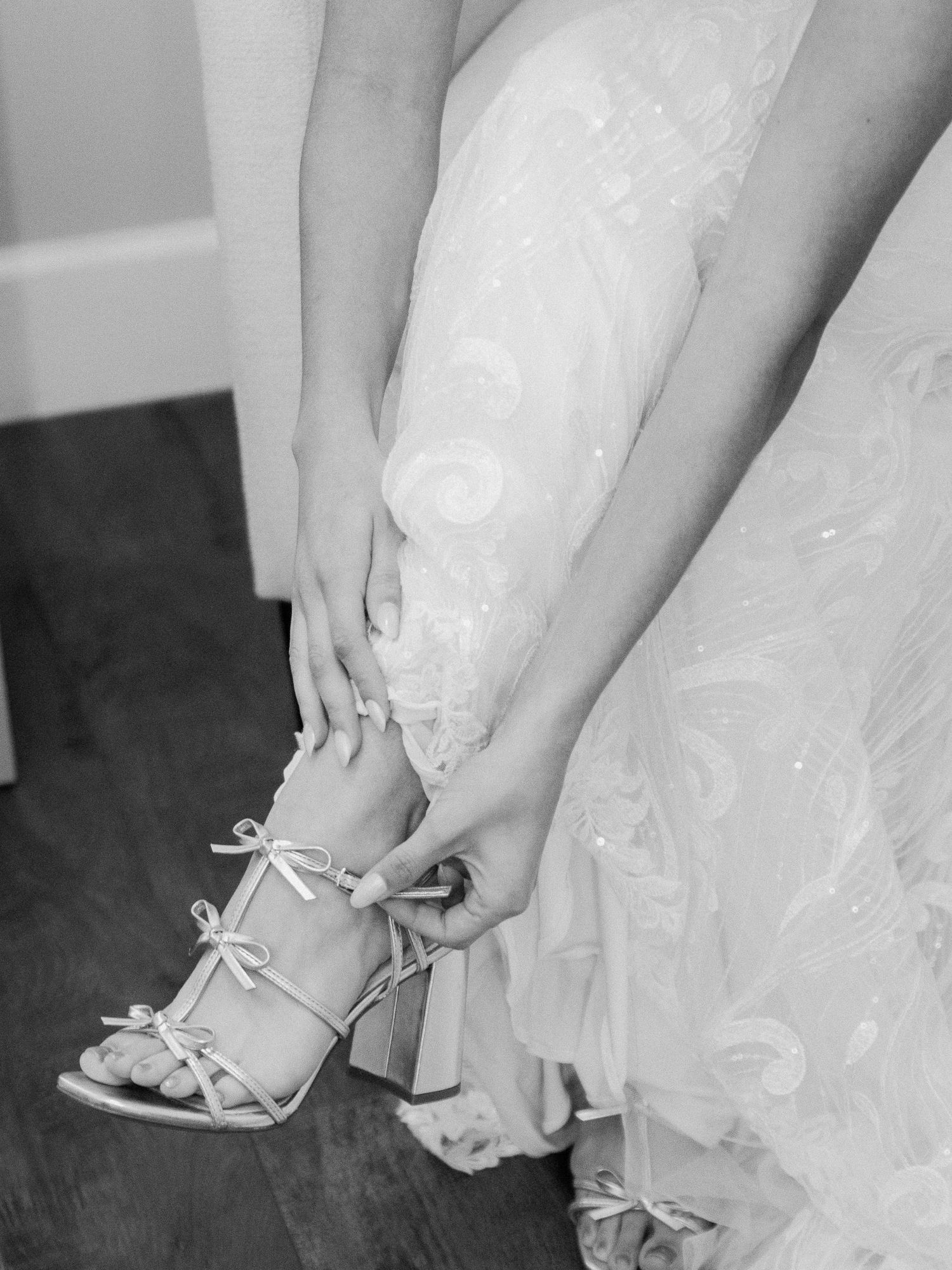 Black and white photo series showing elegant bridal shoes being put on with delicate lace dress details visible.