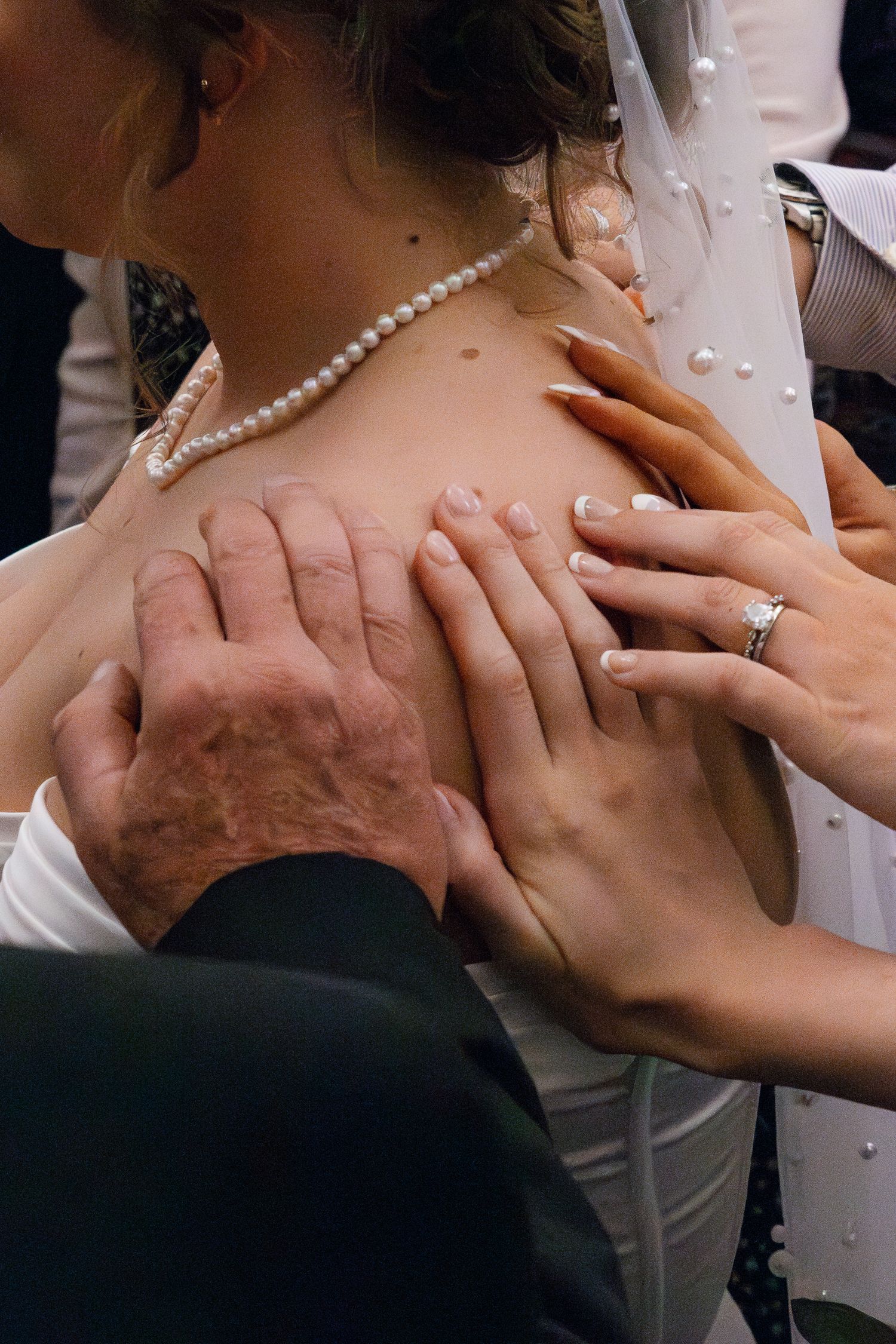 Close-up sequence showing hands wearing wedding rings and pearl necklace during a romantic moment.
