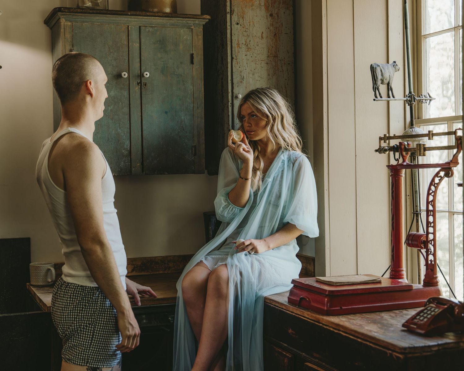 Man and woman in casual clothing having a conversation in a rustic vintage room.