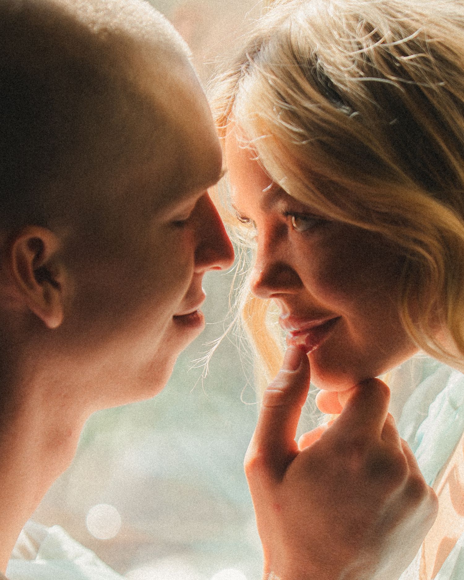 A close-up of a couple nearly kissing, soft warm light highlighting their tender romantic moment.