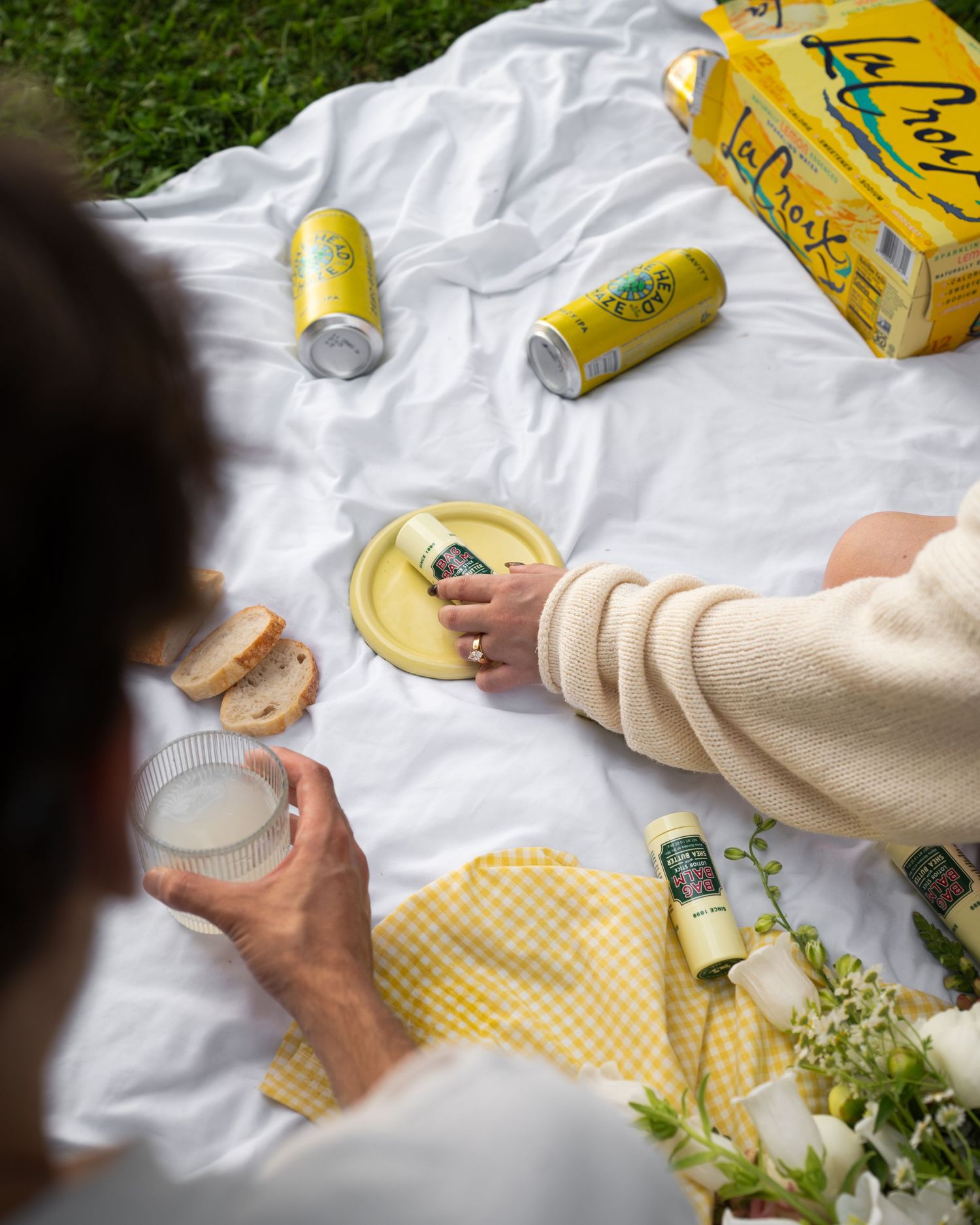 Overhead view of picnic blanket with LaCroix lemon sparkling water cans and bread.