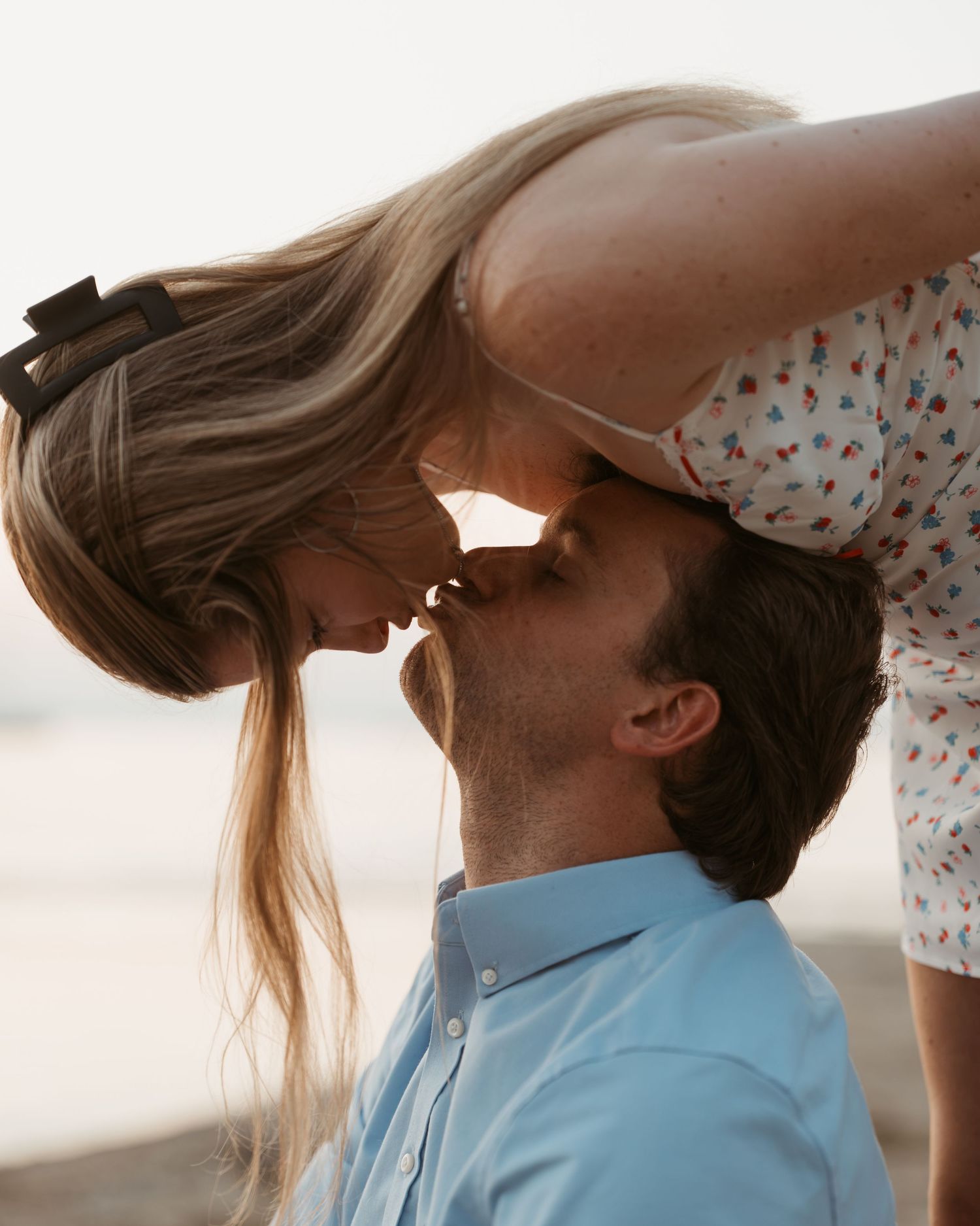 Romantic close-up of couple about to kiss, woman leaning down toward man outdoors.