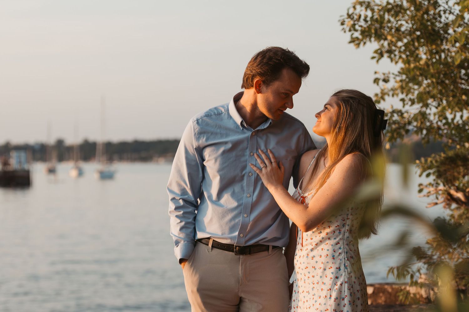 Couple sharing a romantic moment by the waterfront at golden hour sunset.
