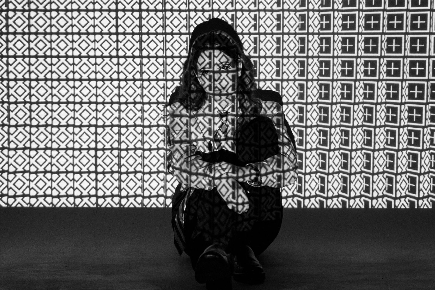 Artistic black and white solo portrait with dramatic projected light.