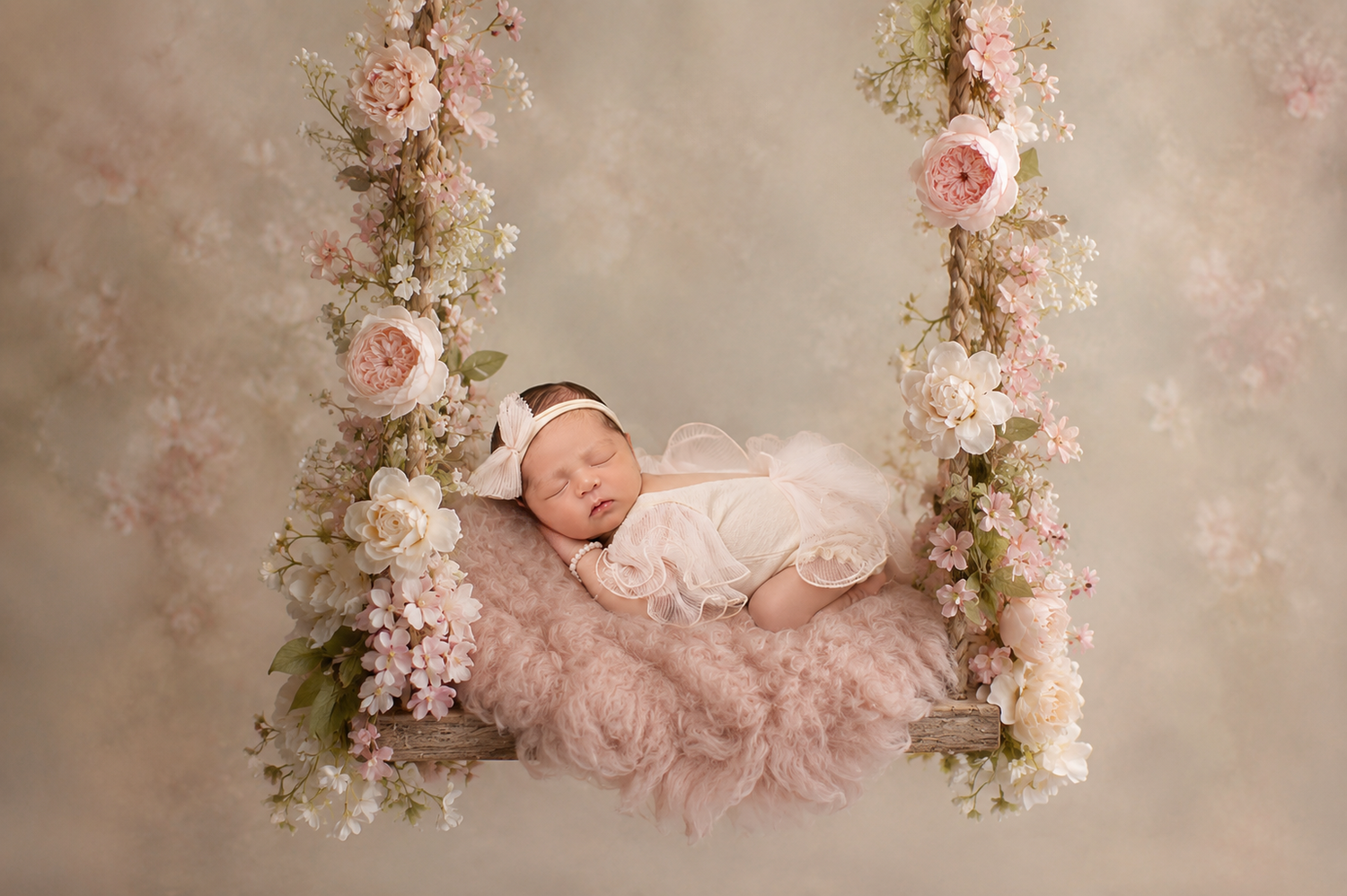 Newborn baby sleeping peacefully on a floral swing decorated with pink roses and soft pink fur.