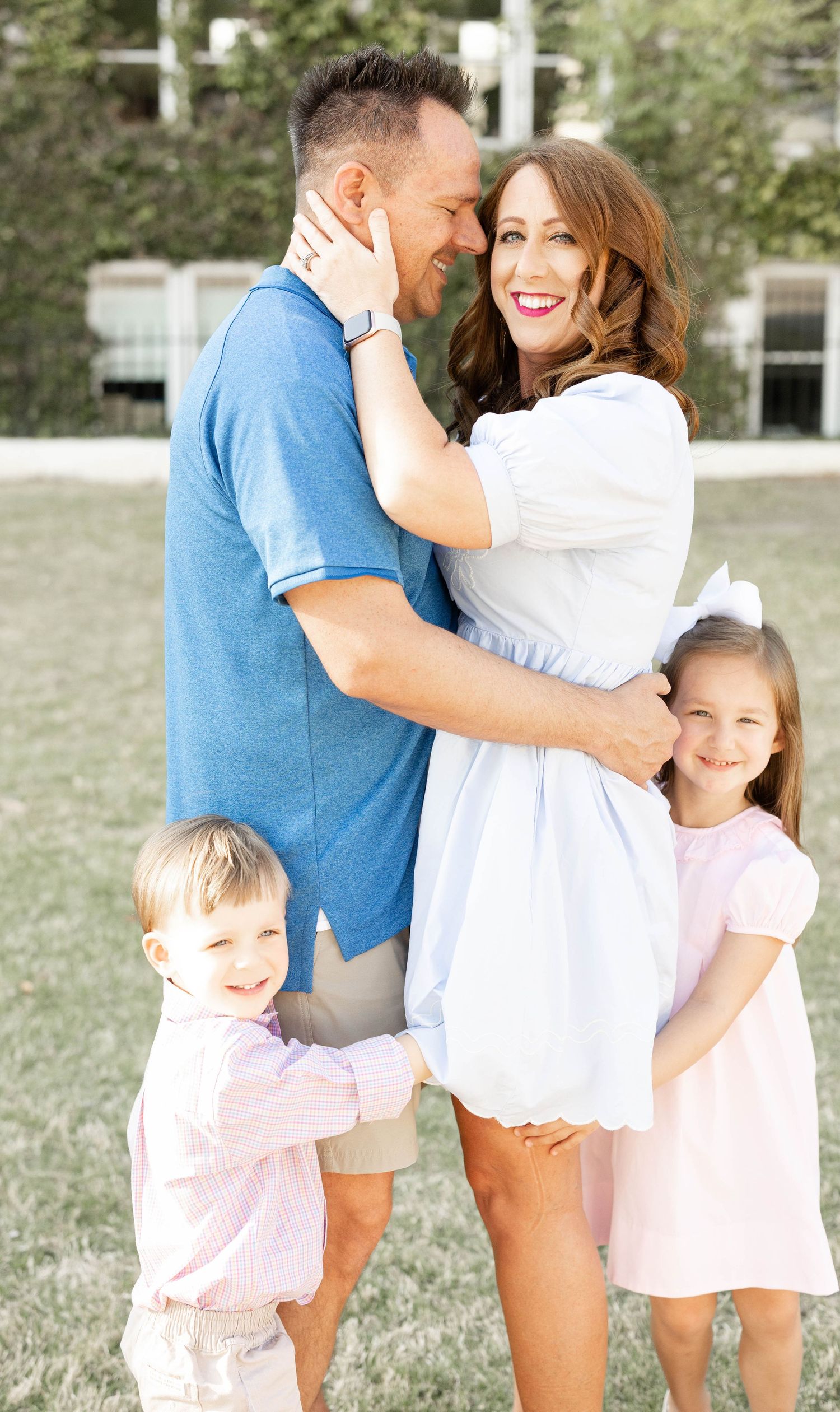 Happy family with two young children embracing outdoors in coordinating blue and pink outfits.