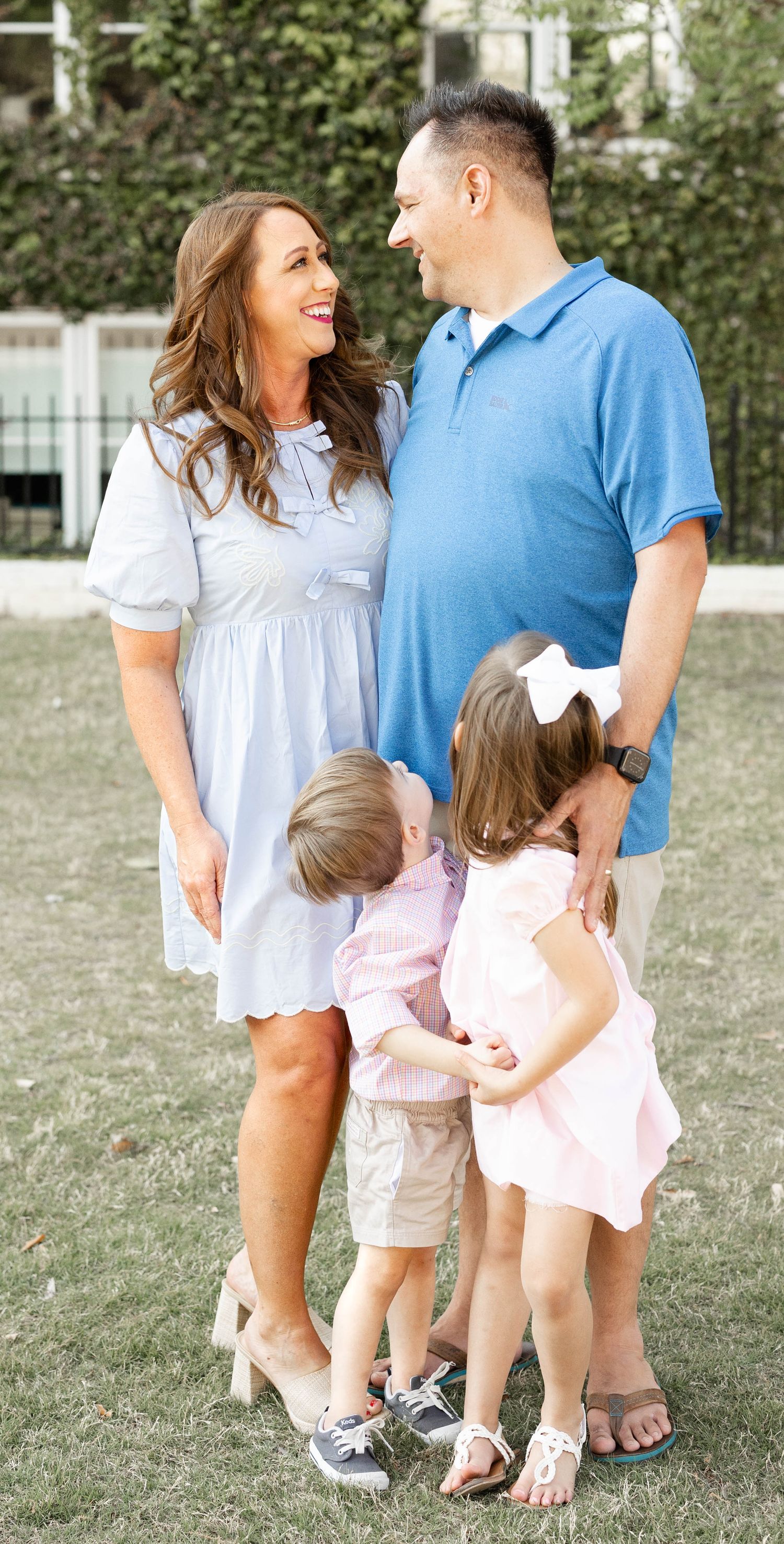 Loving family of four sharing a joyful moment outdoors with parents gazing at each other.