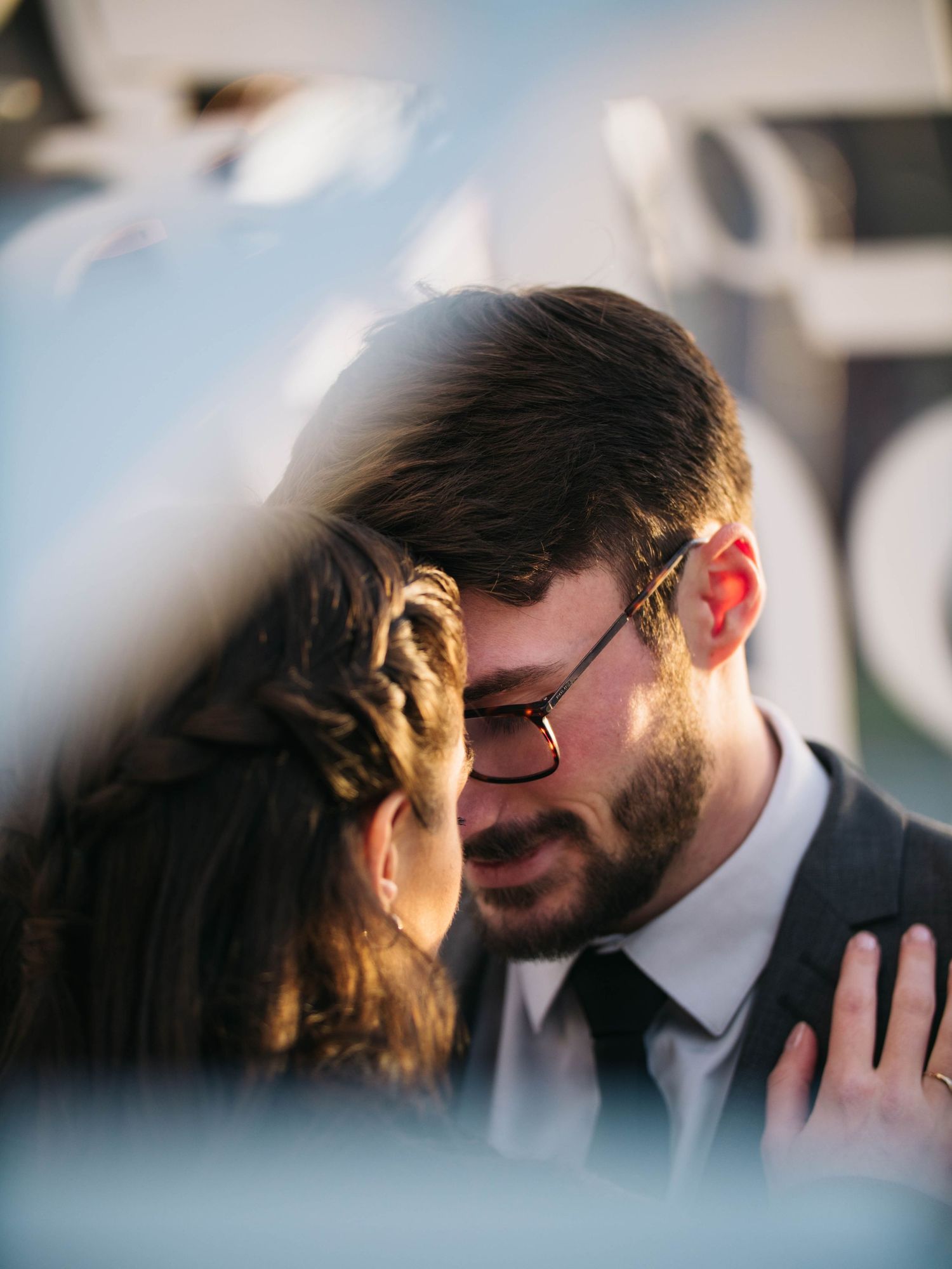 Couple sharing an intimate moment, man wearing glasses and tie, woman resting hand on his chest.