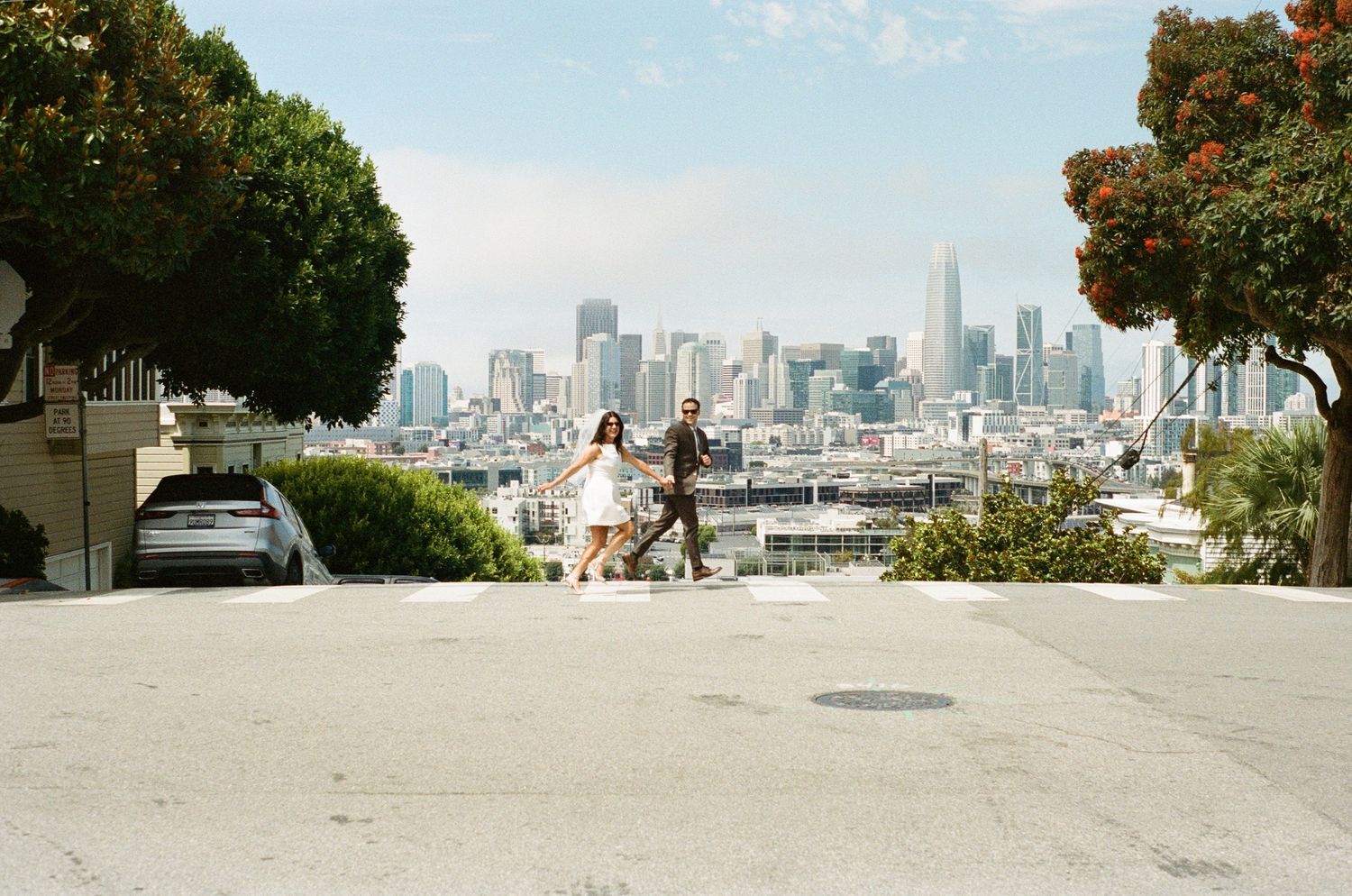 Couple dancing on a steep San Francisco street with the city skyline and Transamerica Pyramid in the background.