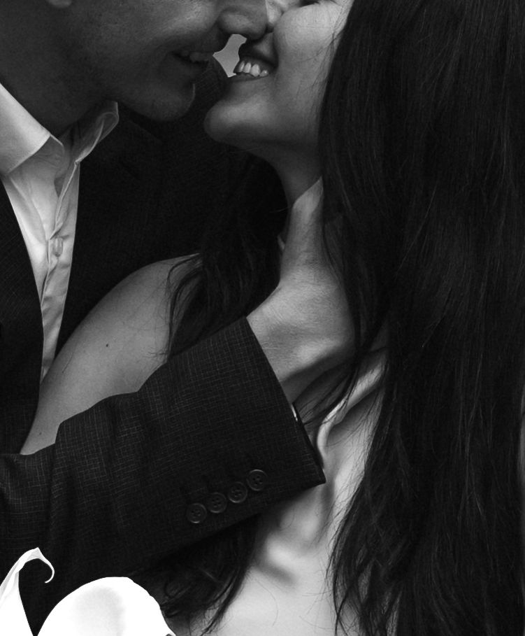 An intimate black and white photograph capturing a romantic close-up moment between two people about to kiss.