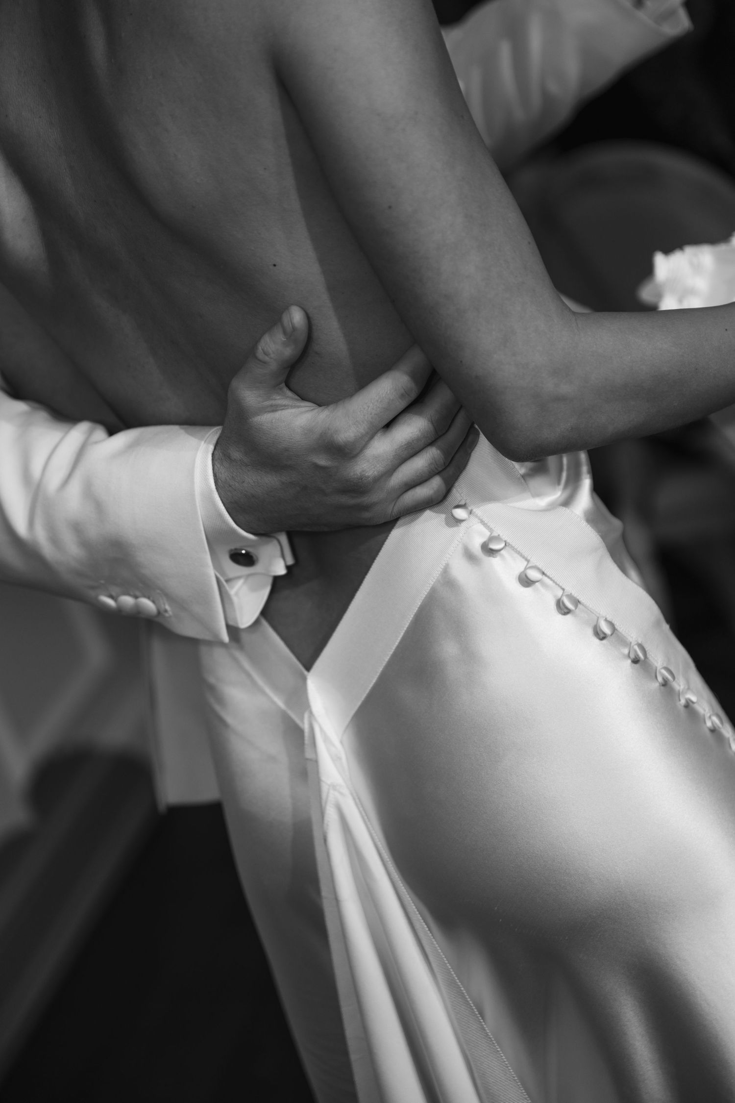 Close up detail of buttons being fastened on white wedding dress.