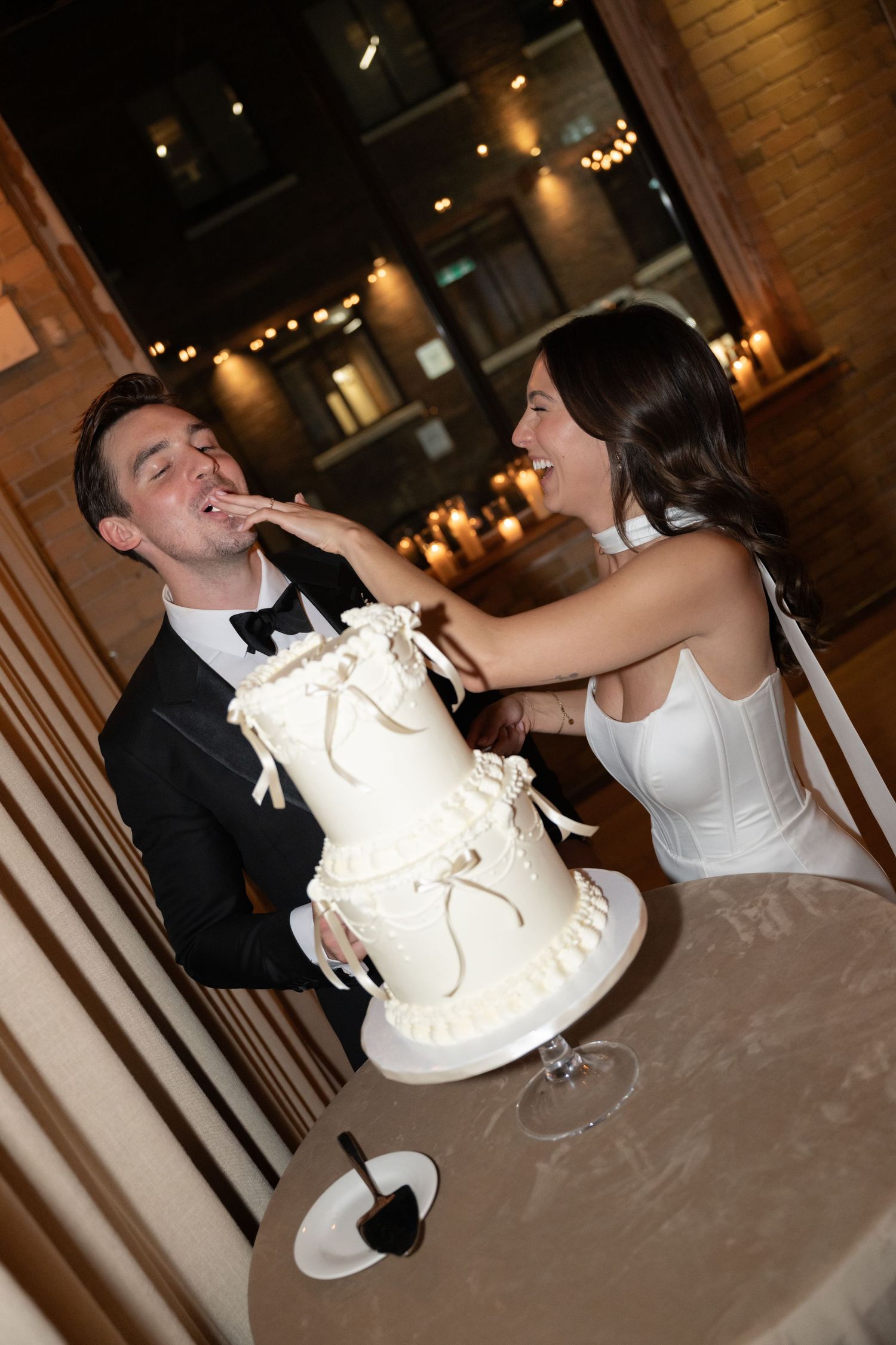 Classic wedding cake-cutting moment as couple playfully feeds cake to each other during reception.